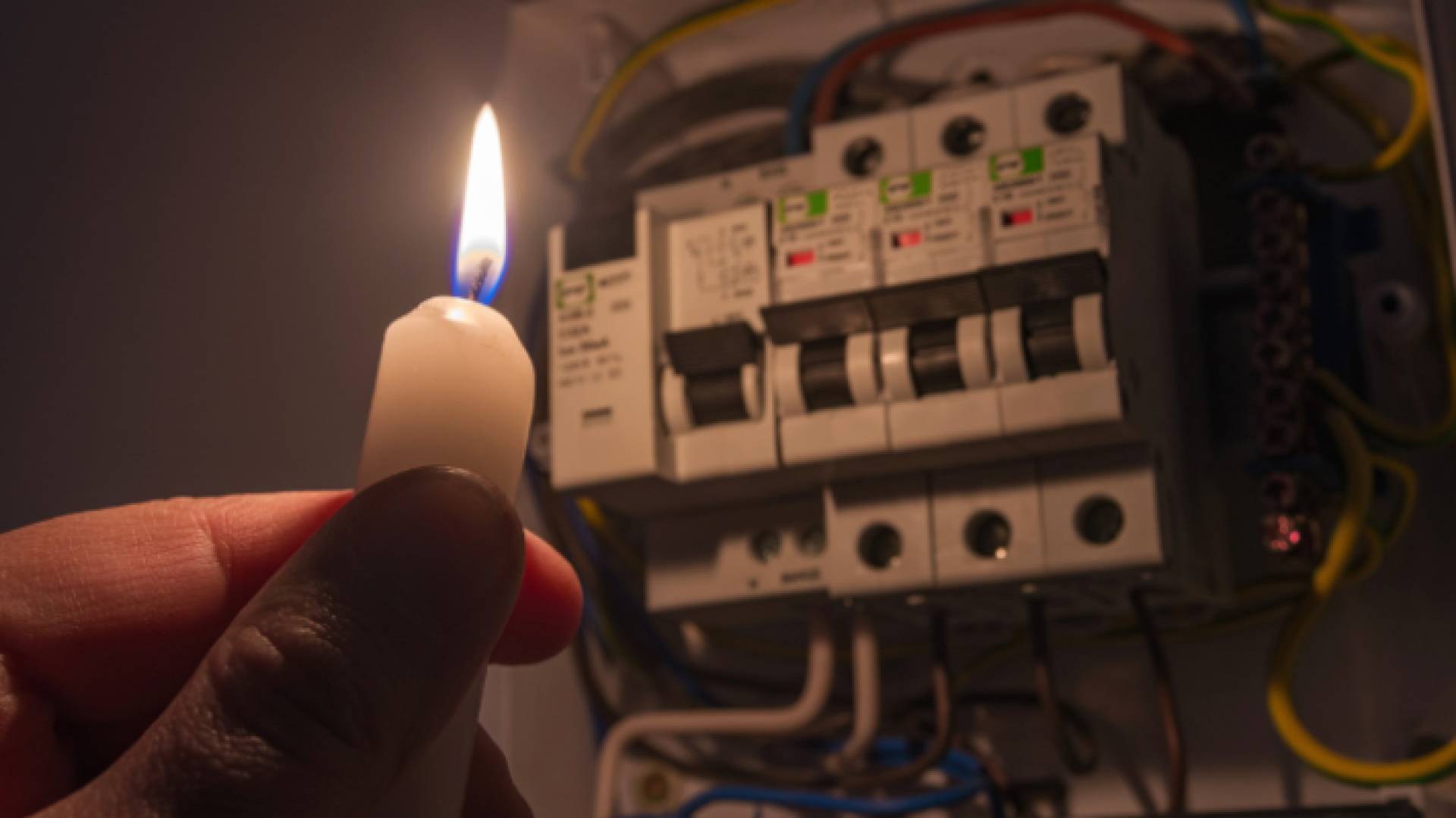 شخص يحمل شمعة بسبب انقطاع الكهرباء