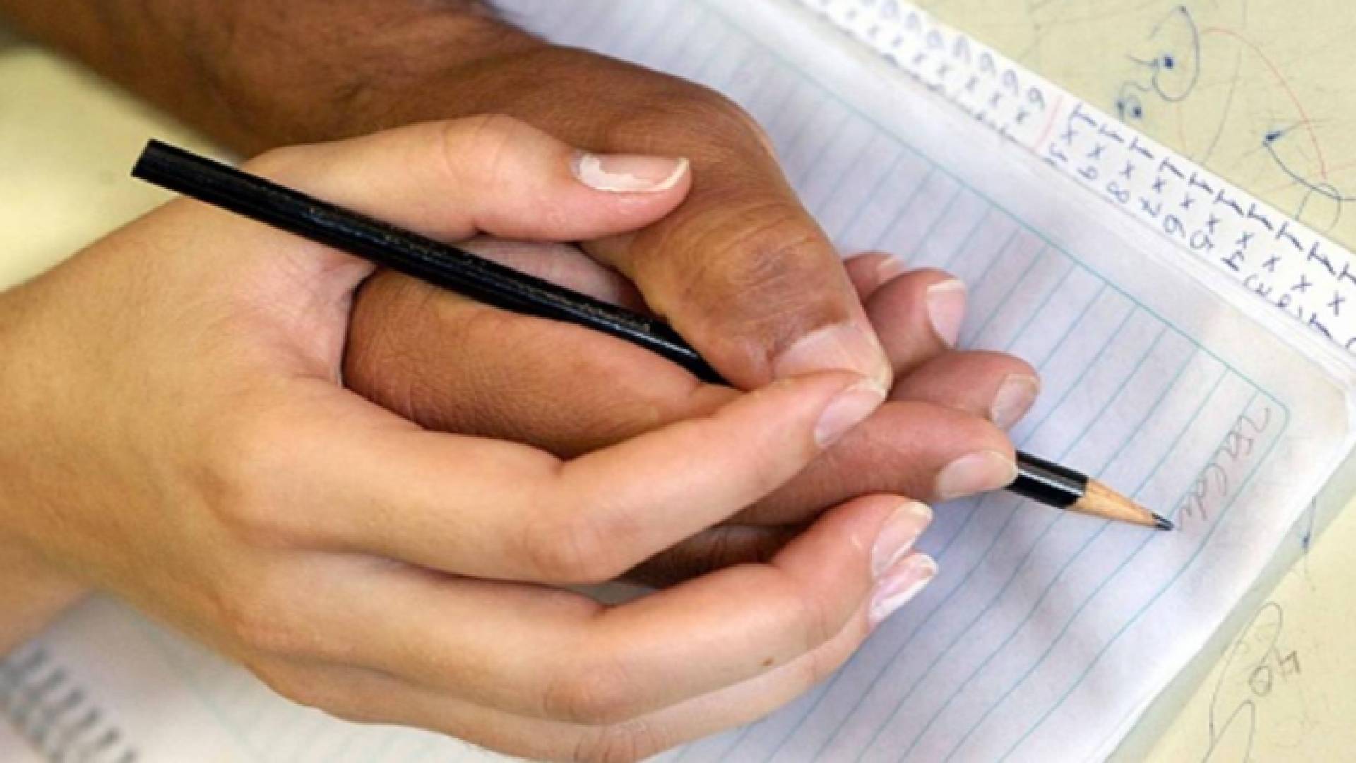 صورة تعبيرية لشخص يعلم أحد كبار السن الكتابة