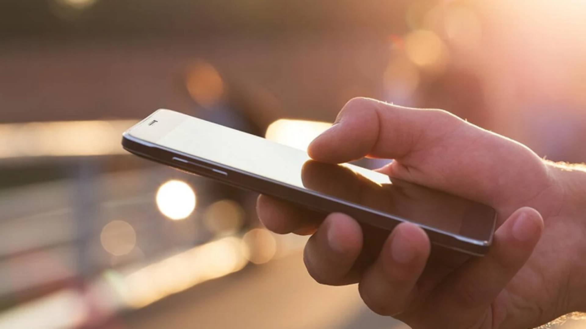 شخص يحمل هاتف خلوي "تعبيرية"