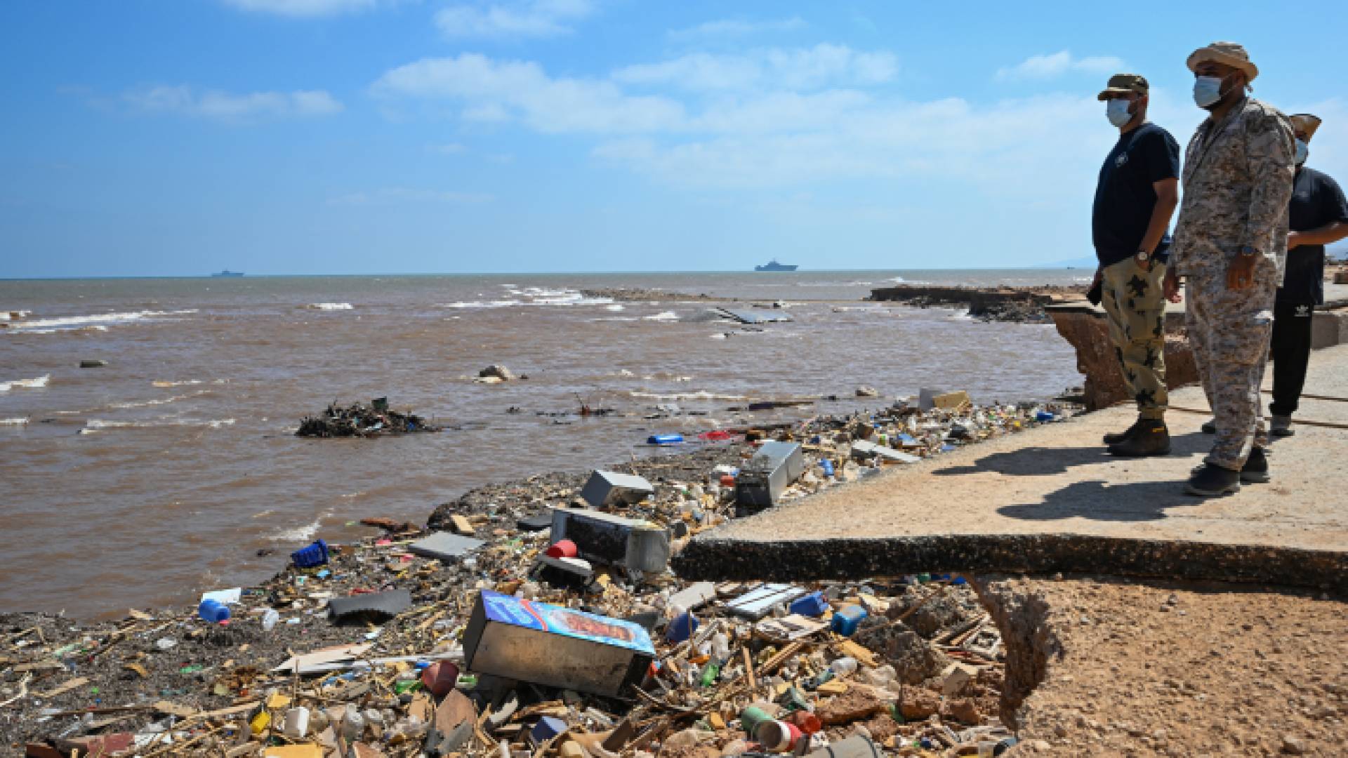 أشخاص يراقبون حركة المياه للبحث عن مفقودين في درنة