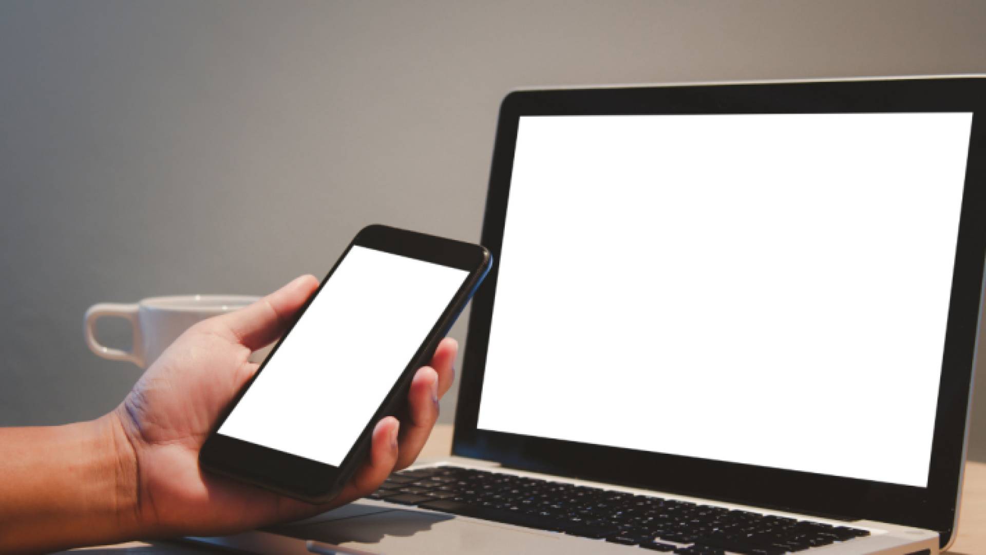 شخص يحمل جهاز خلوي ويتابع عبر جهاز كمبيوتر "تعبيرية"