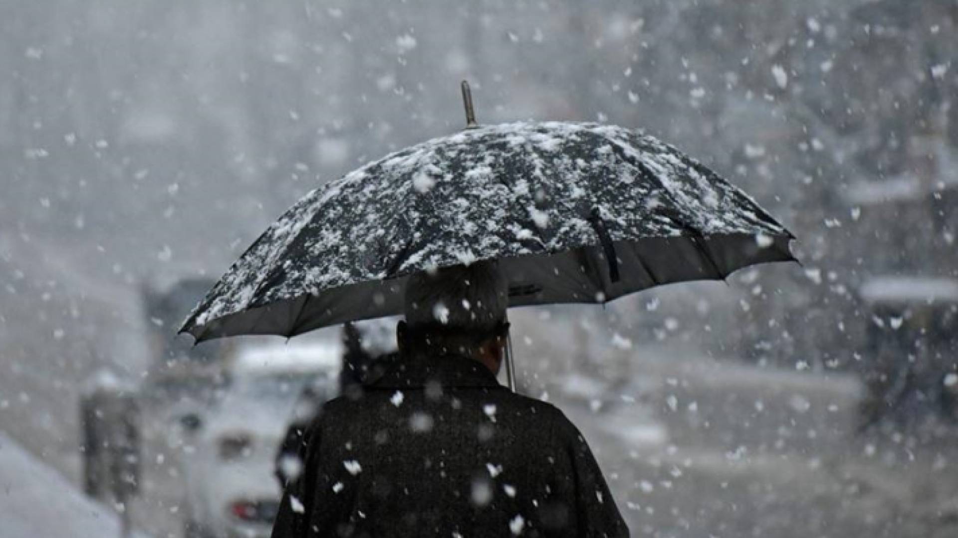 صورة أرشيفية لشخص يحمل مظلة أثناء تساقط الثلوج