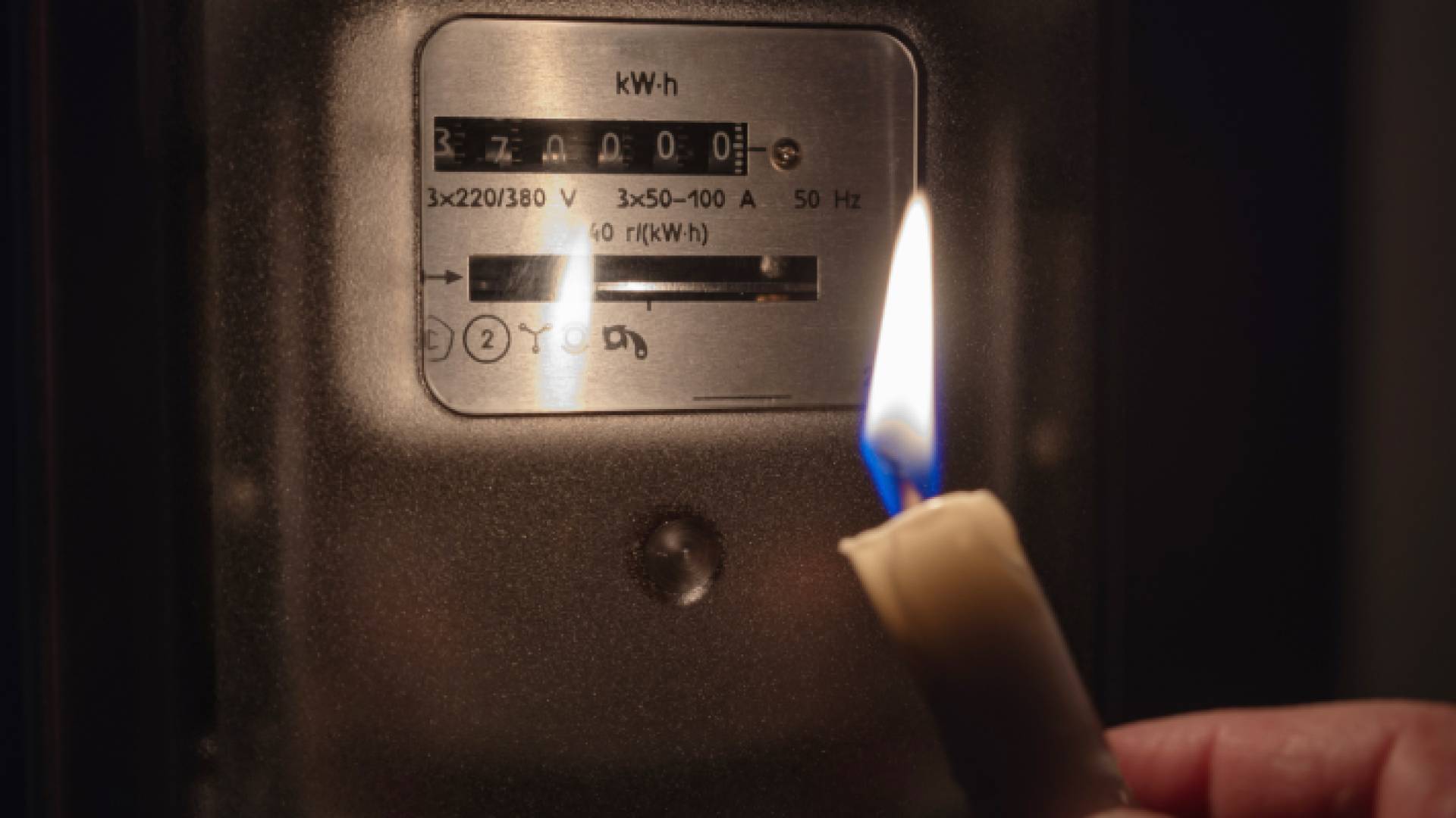 شخص يضيء شمعة بالقرب من عداد كهرباء "تعبيرية"