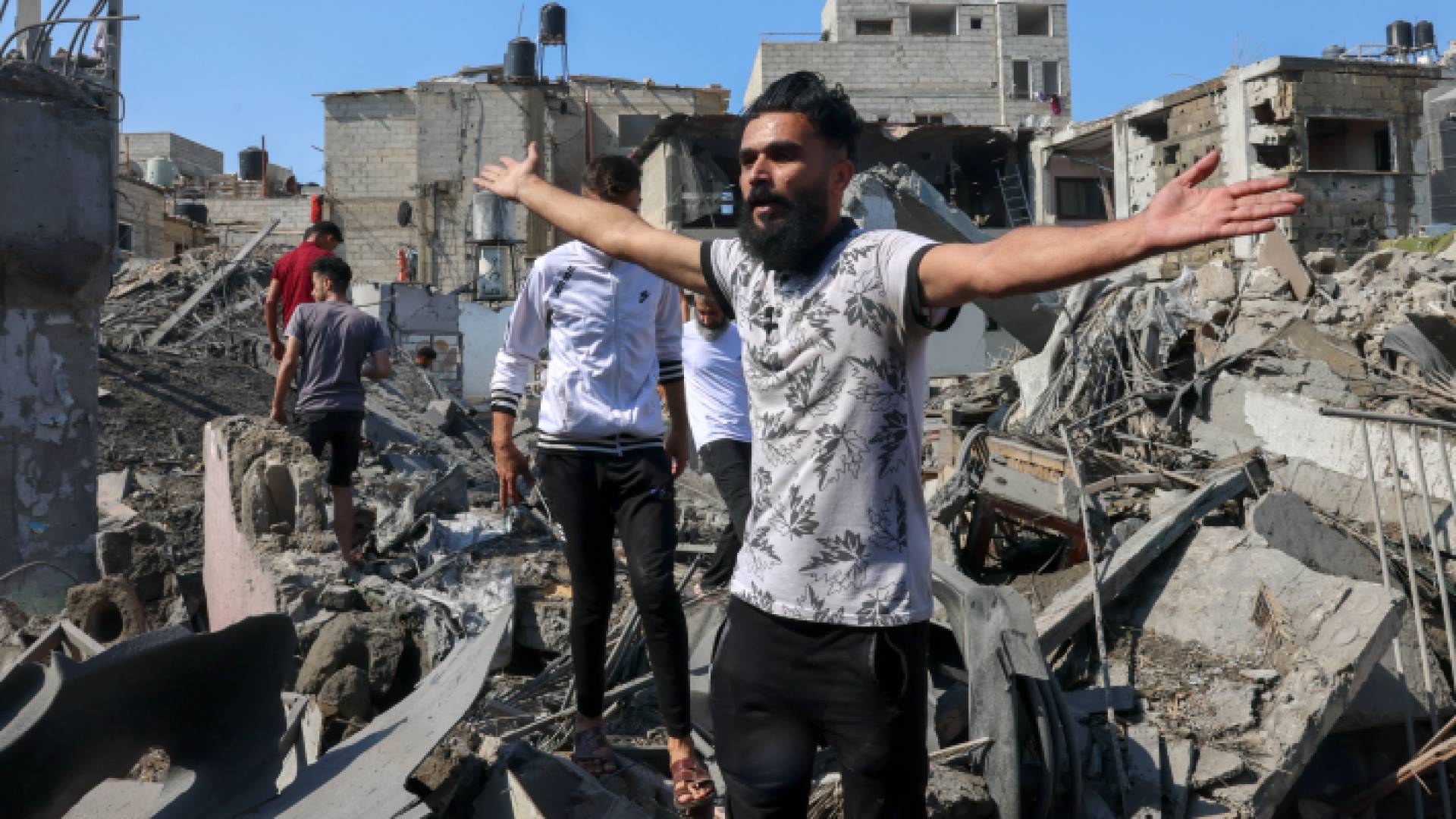 غزيون بالقرب من منازلهم التي دمرها الاحتلال