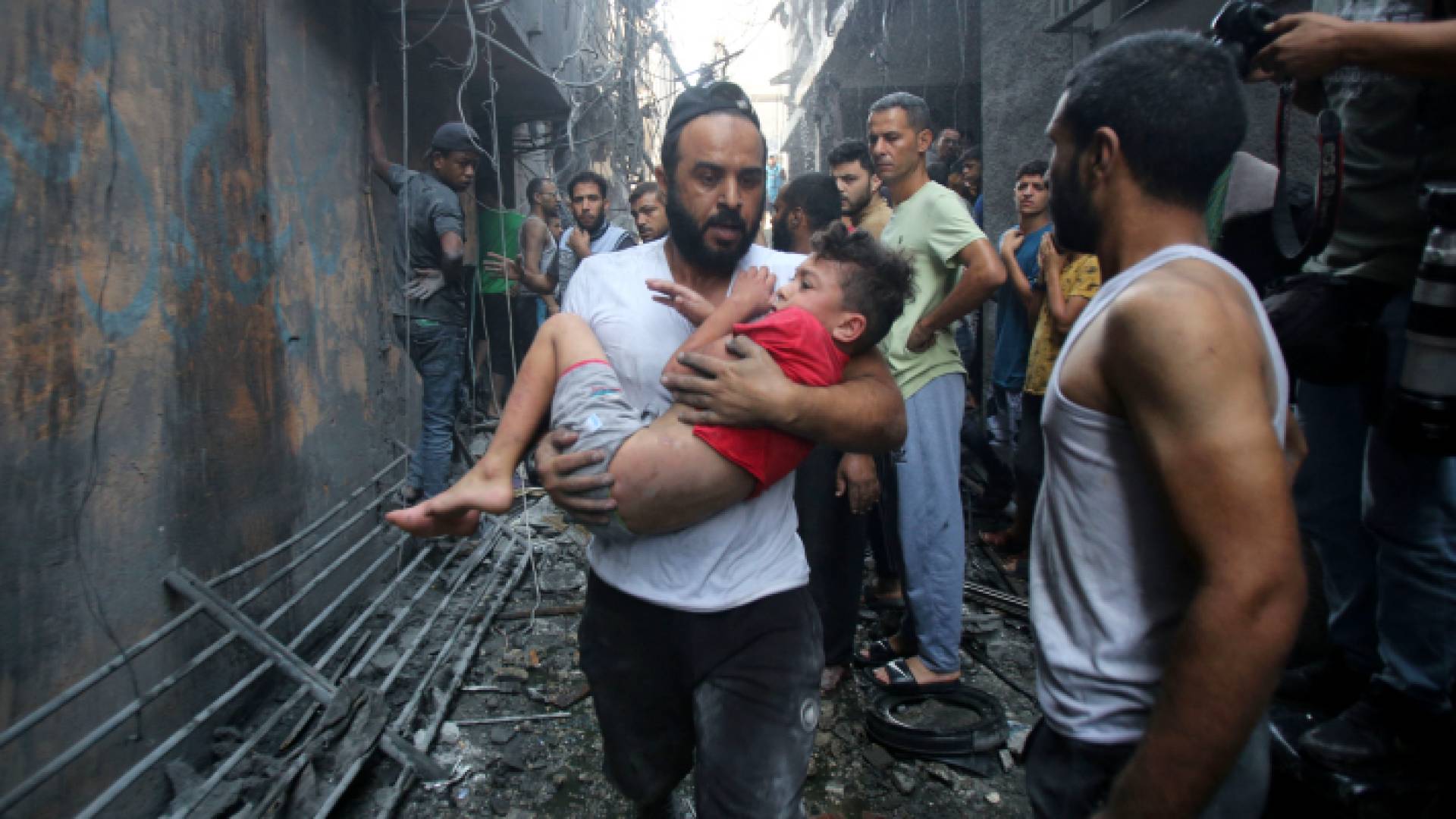 فلسطيني يحمل طفله بعد قصف منزله في قطاع غزة