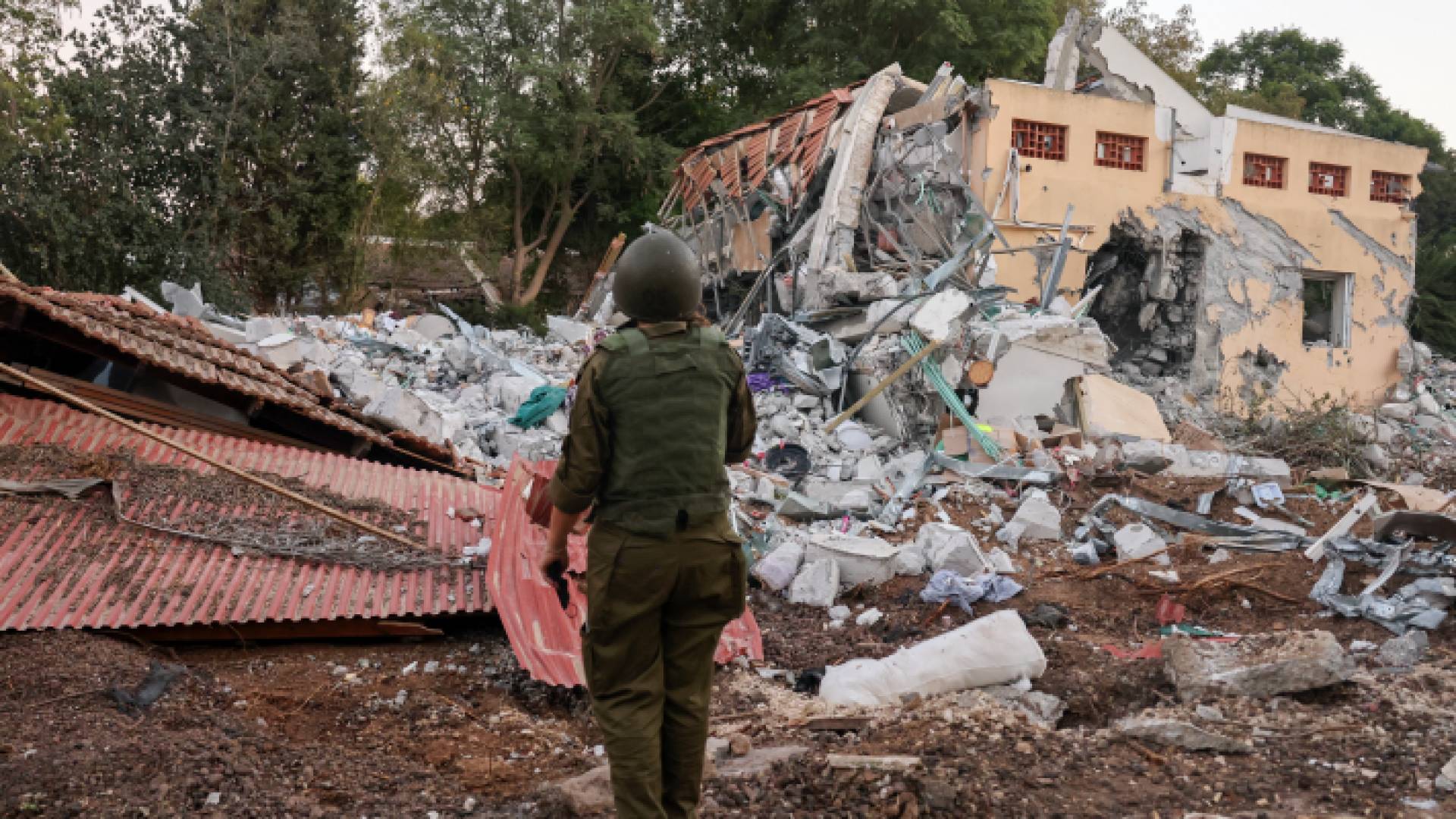 جندي إسرائيلي يقف أمام منزل مدمر