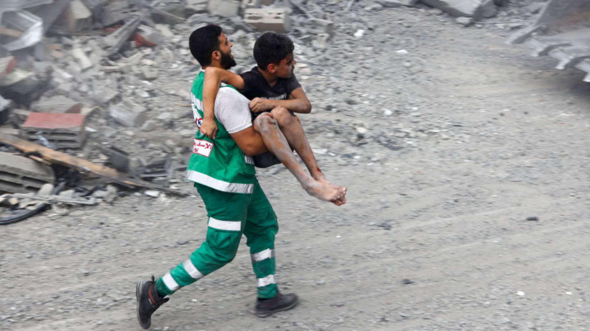مسعف فلسطيني يحمل طفلا بعد قصف منزله في قطاع غزة