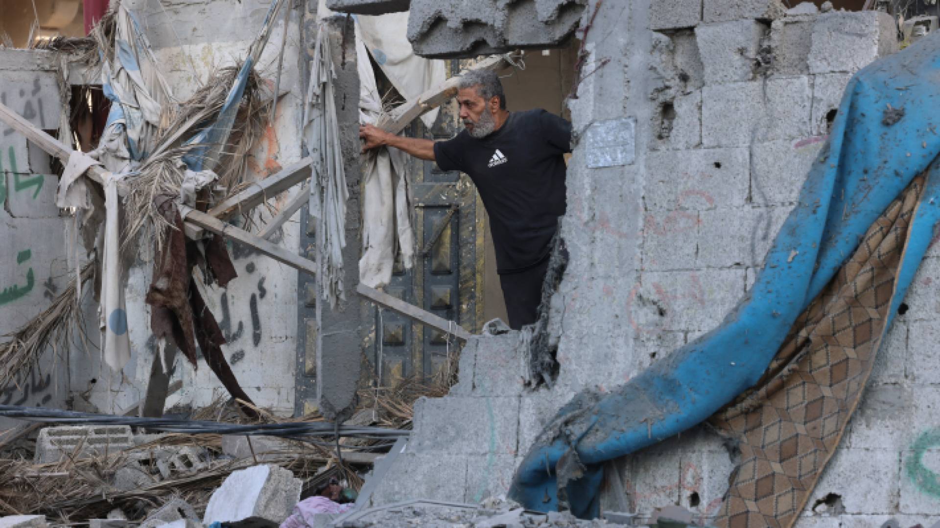 فلسطيني يقف عند مدخل منزله المدمر في قطاع غزة