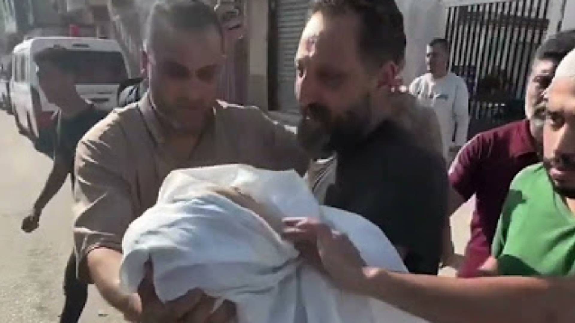 فلسطيني يحمل ابنه الشهيد في قطاع غزة