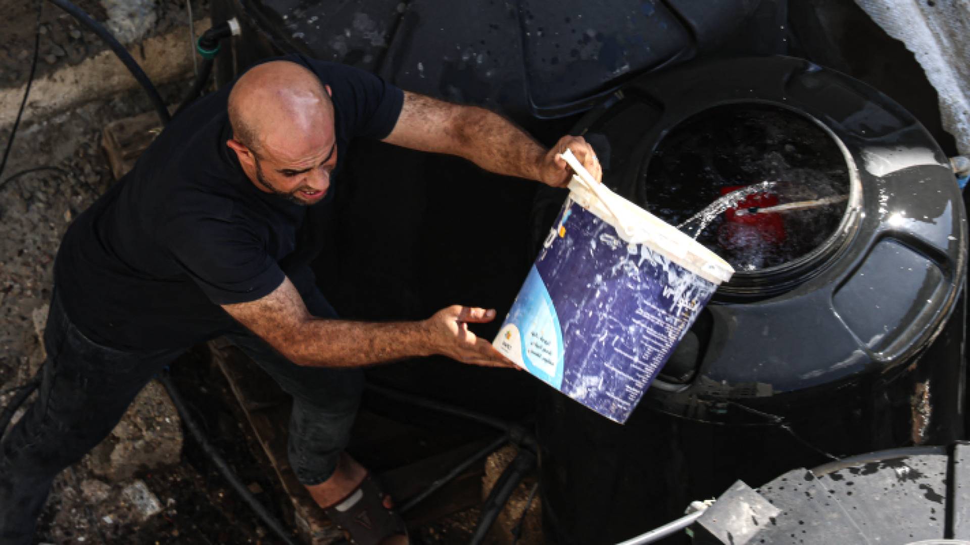 فلسطيني يعبئ خزان مياه في قطاع غزة