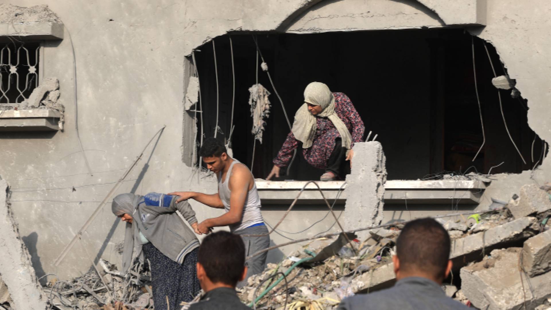 فلسطينيون يحاولون الخروج من بين ركام منزل مدمر في قطاع غزة