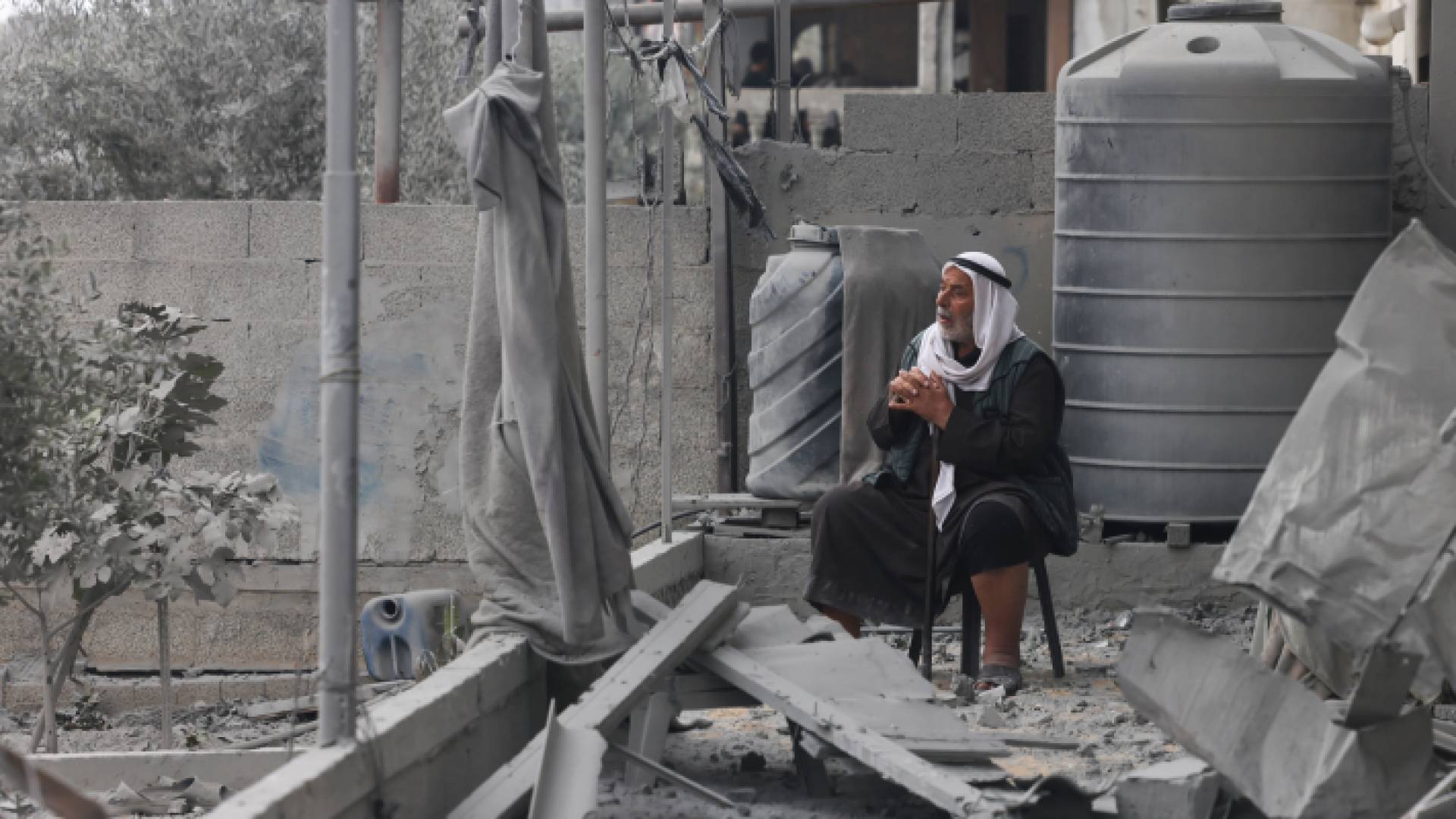 مسن فلسطيني يجلس فوق منزل تعرض للقصف في غزة
