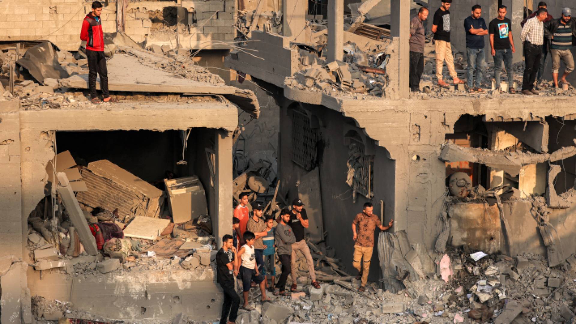 فلسطينيون يقفون على أنقاض دمار خلفه قصف الاحتلال الإسرائيلي في قطاع غزة