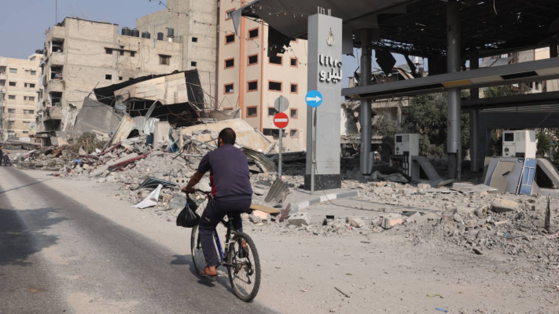 فلسطيني يقود دراجته امام أنقاض منازل قصفها الاحتلال الإسرائيلي