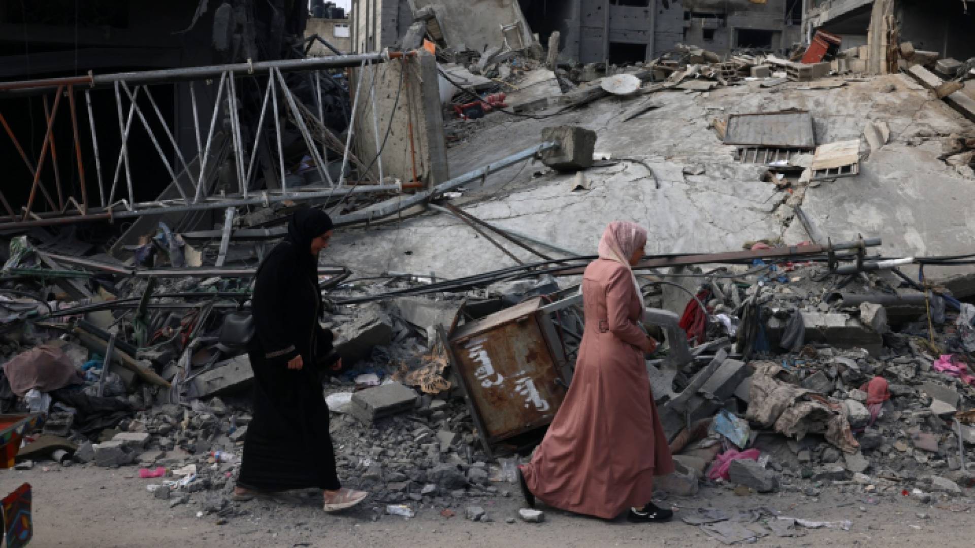 فلسطينيتان تمشيان أمام دمار خلفه قصف الاحتلال الإسرائيلي