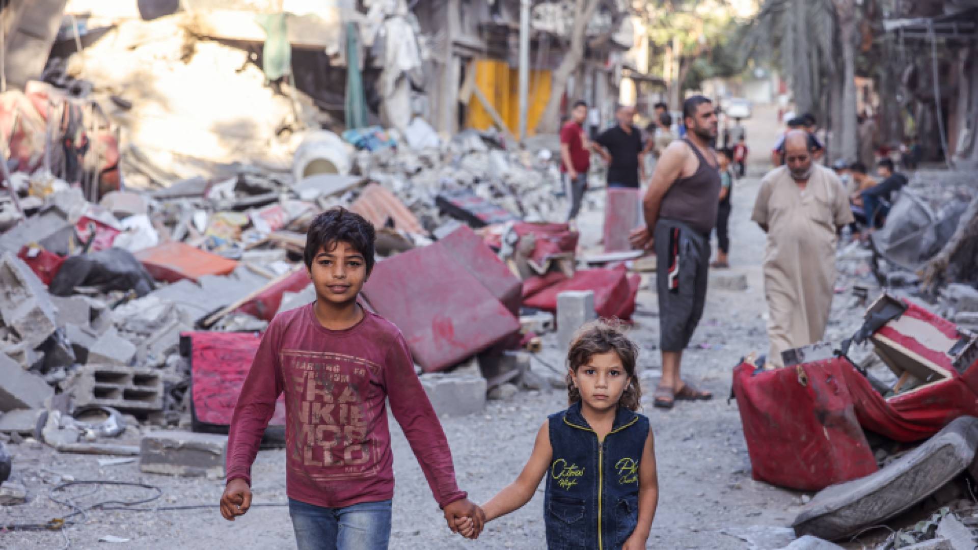 فلسطينيون يسيرون في شارع مدمر في أعقاب غارات الاحتلال