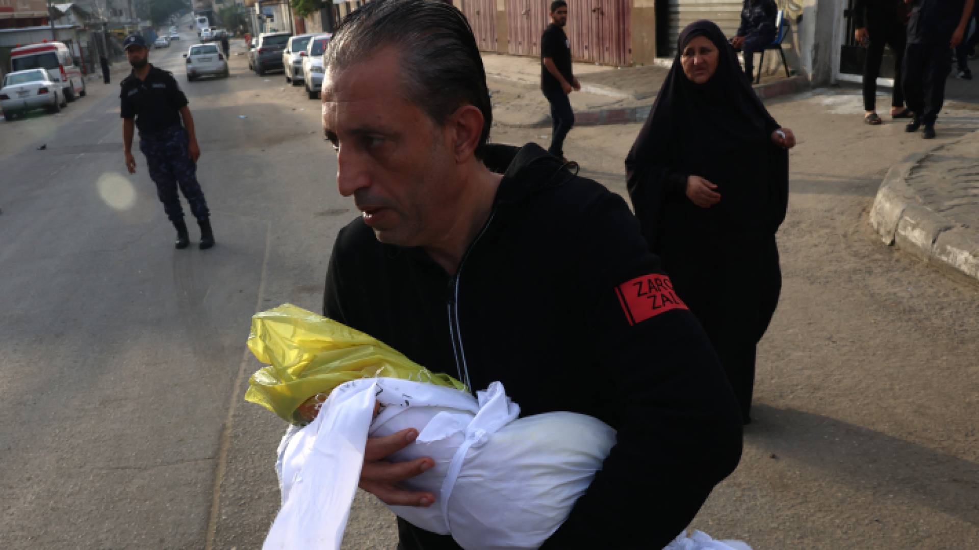 فلسطيني يحمل صغيره الشهيد في قطاع غزة