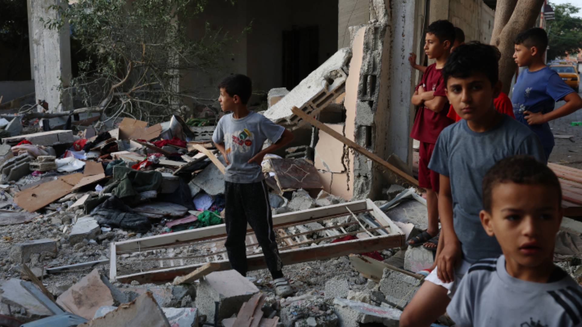 أطفال يقفون بالقرب من أحد المنازل التي دمرها قصف الاحتلال