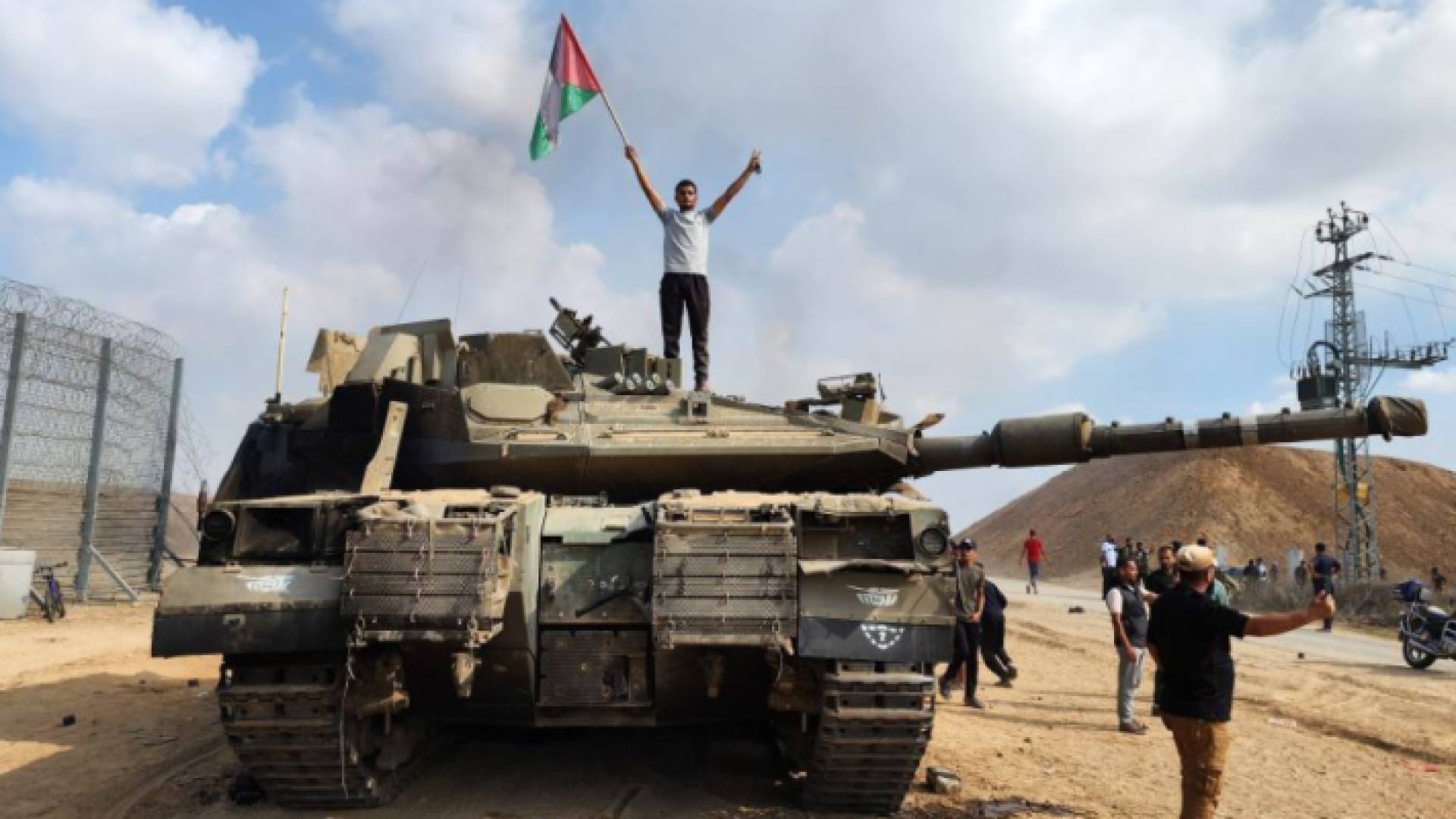 فلسطيني يرفع علم دولة فلسطين أعلى دبابة مدمرة للاحتلال
