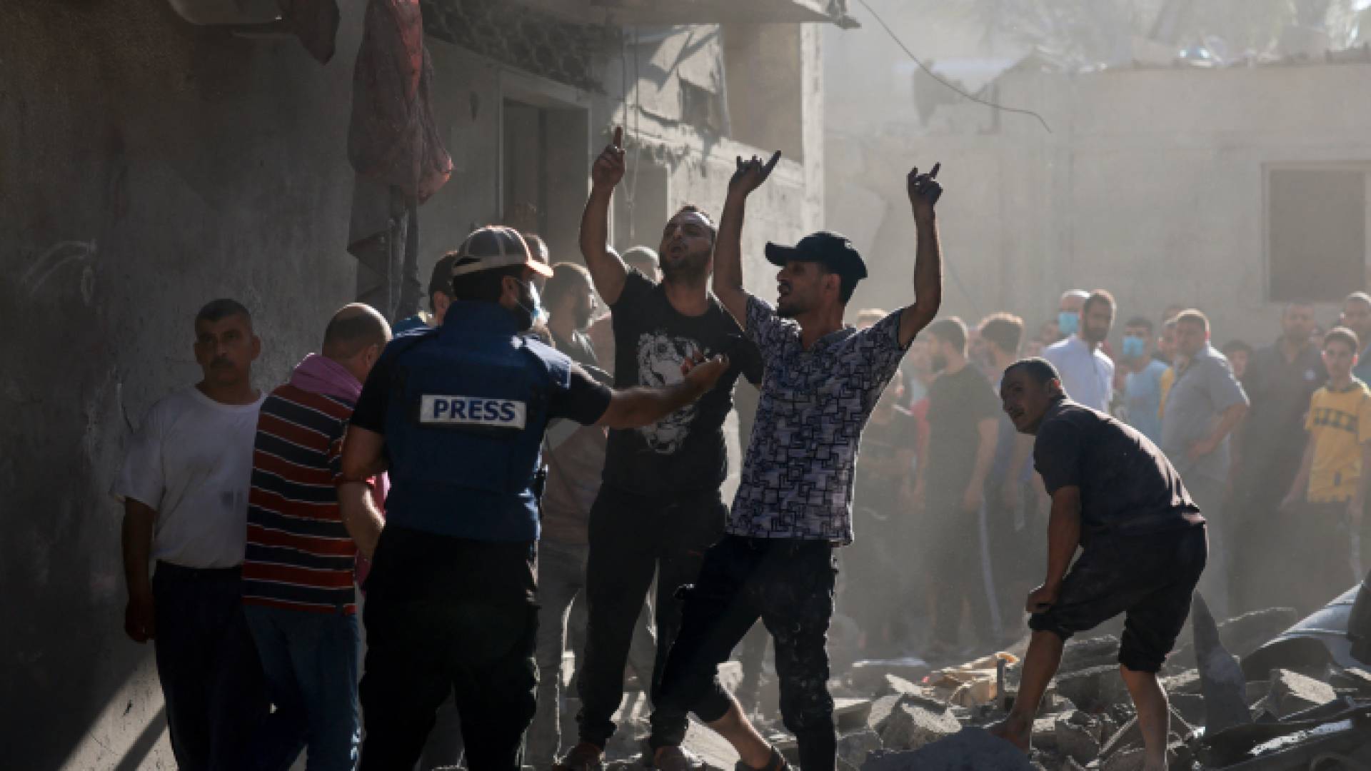 فلسطينيون يسيرون وسط ركام منزل تعرض للقصف