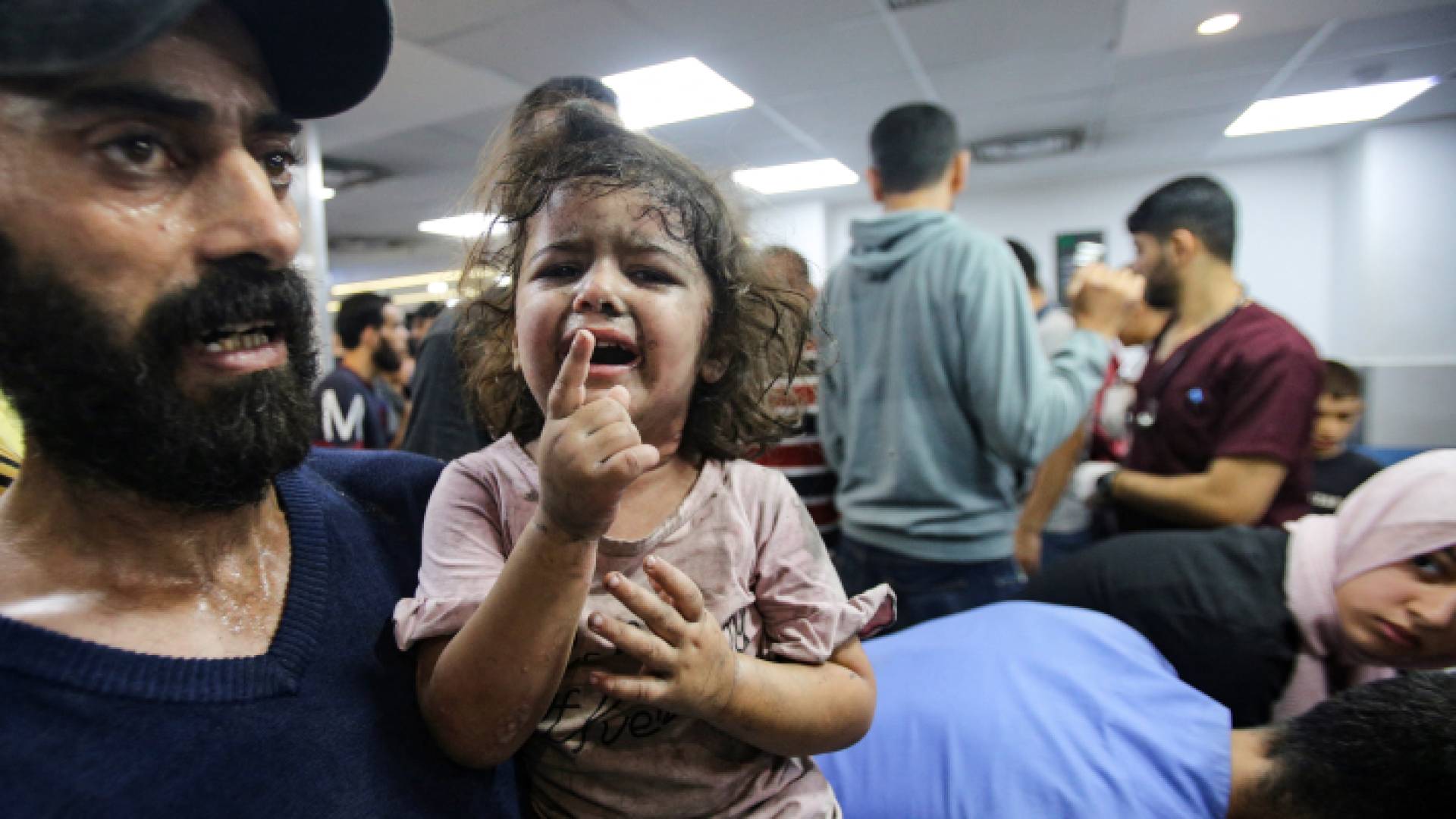 فلسطيني يحمل طفلة مصابة بقصف الاحتلال