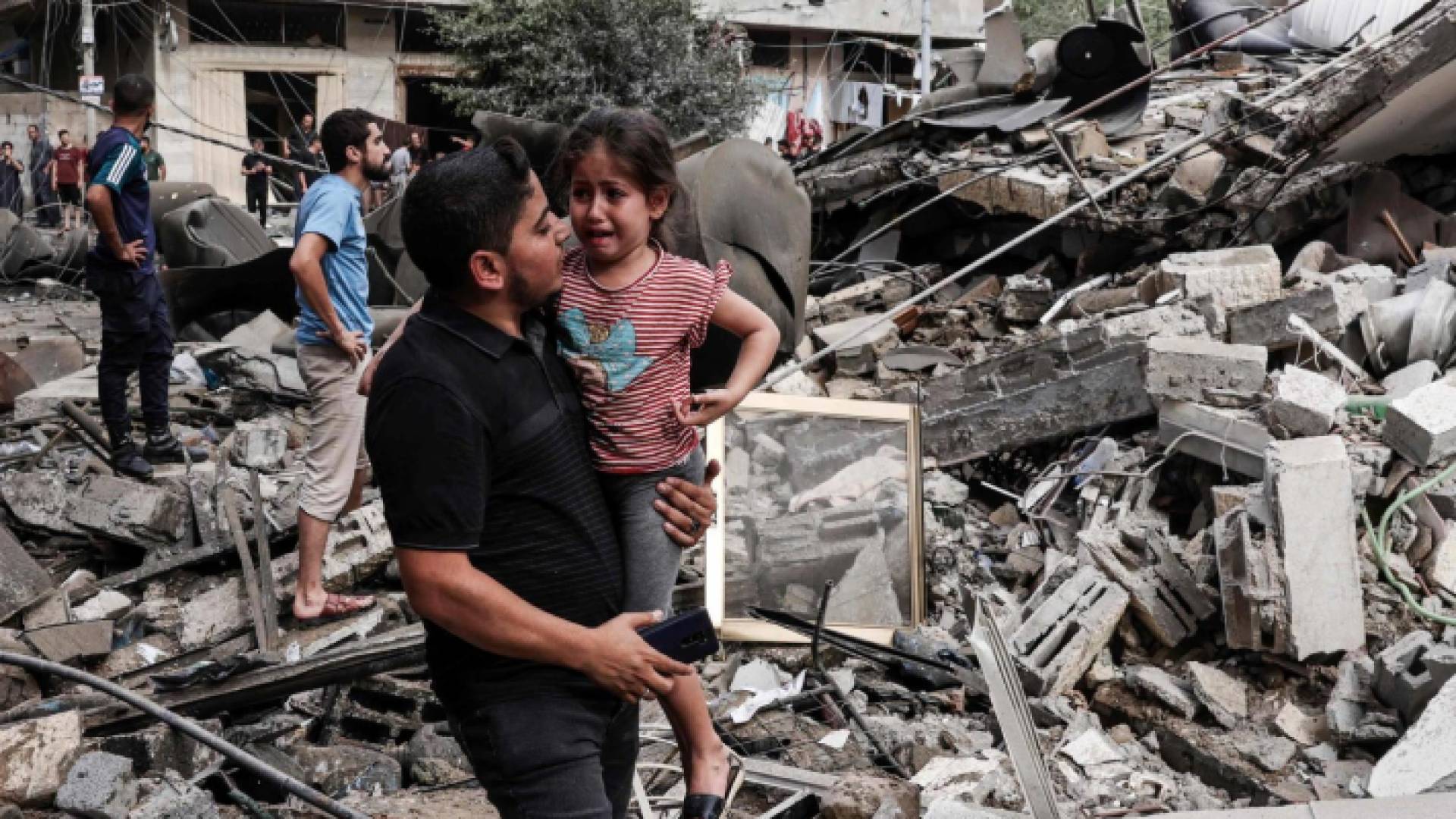 شاب يحمل صغيرة وسط الدمار في غزة
