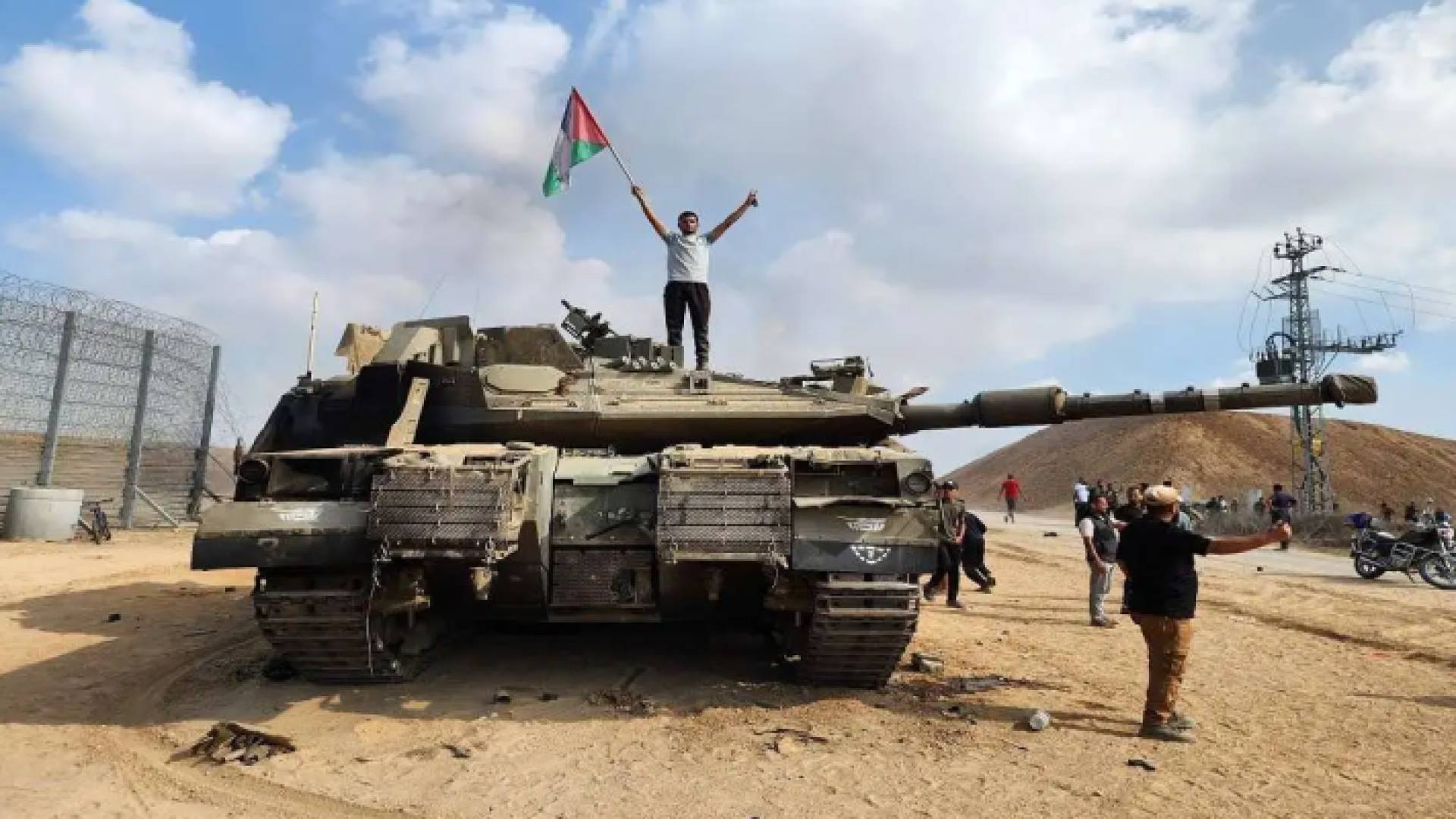 شاب فلسطيني يعتلي دبابة مدمرة للاحتلال ويرفع علم دولة فلسطين