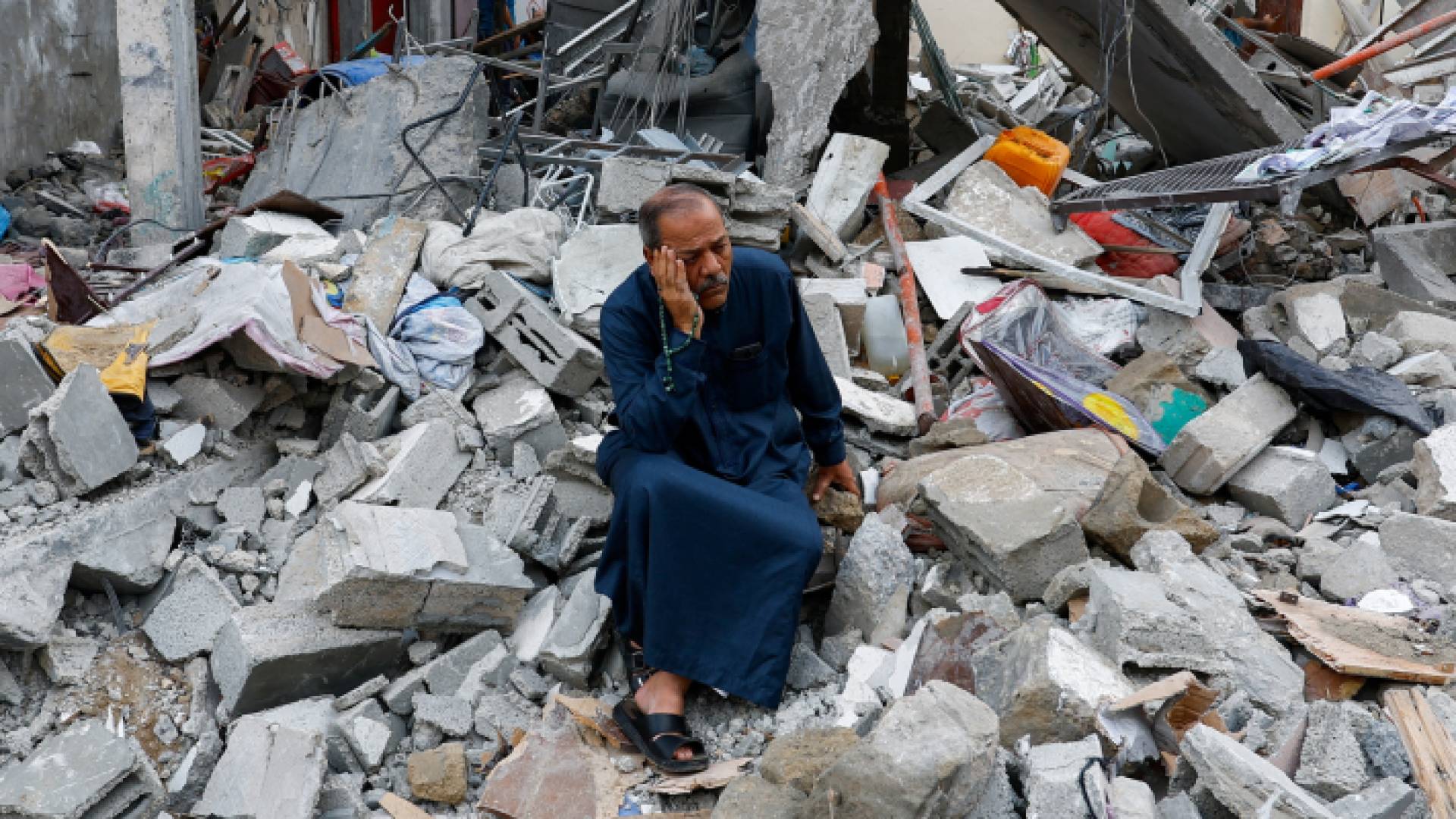 فلسطيني يجلس فوق الركام في غزة