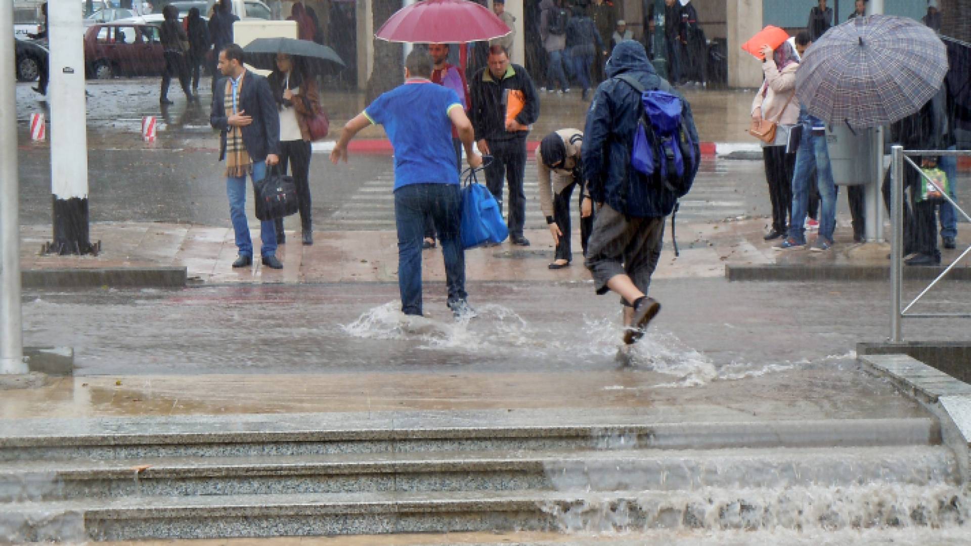 أردنيون يمشون تحت الأمطار في أحد شوارع العاصمة عمان