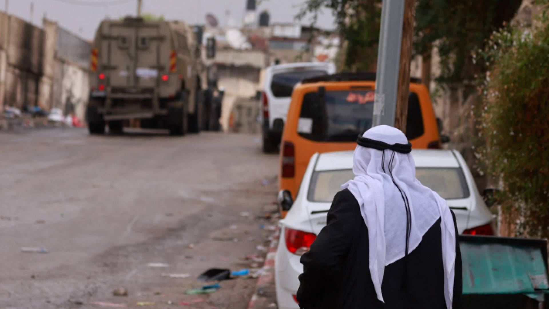 رجل فلسطيني يرمي نظره على اقتحام مركبات الاحتلال مدينة طولكرم