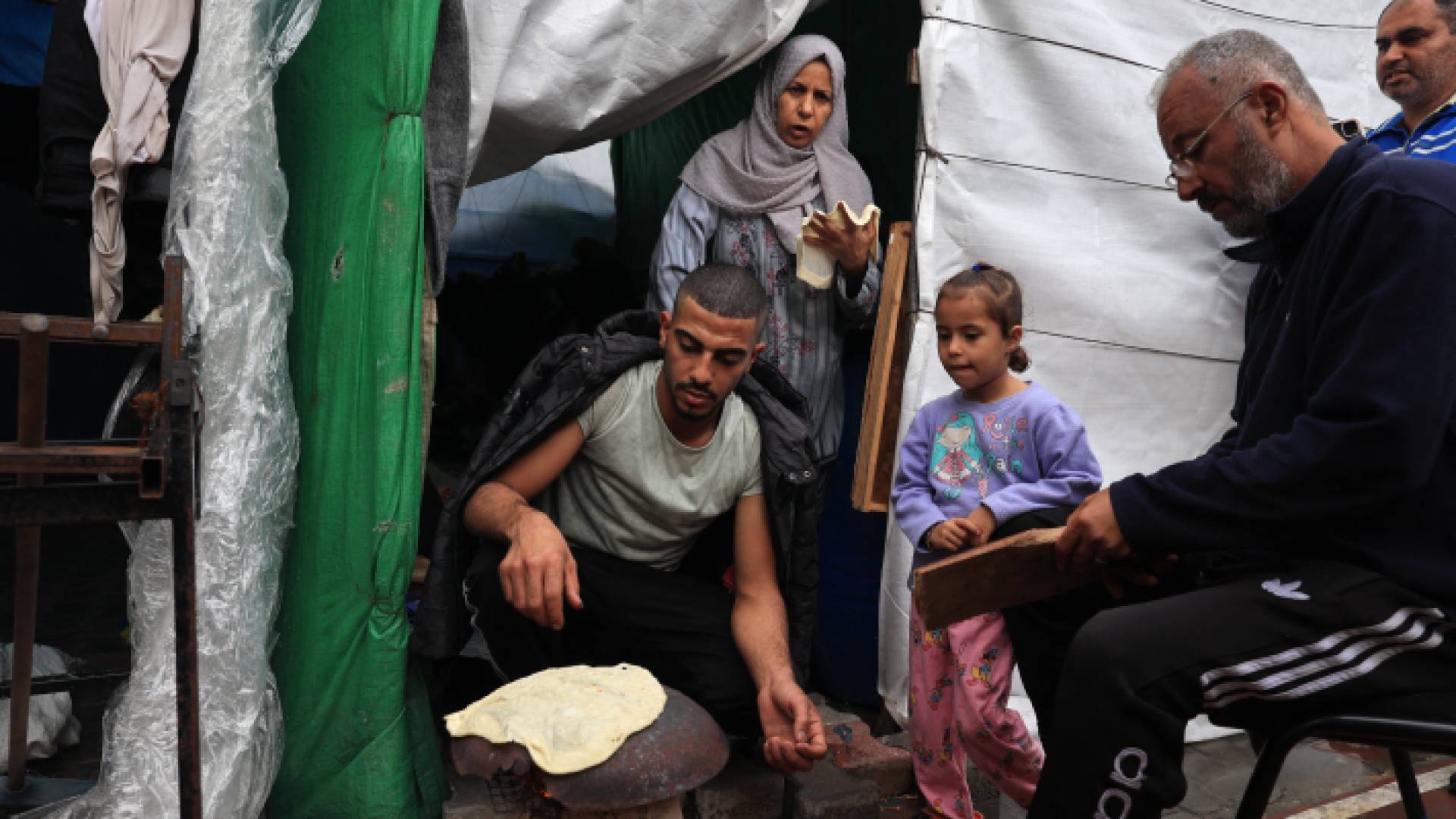 نازحون يقومون بالخبز أمام خيمتهم جنوب غزة