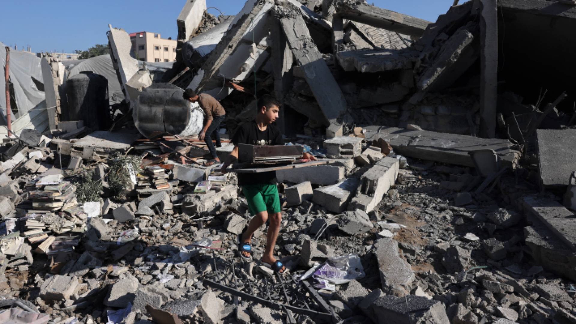 فلسطينيون يرفعون أنقاض أحد المباني بعد هدمه على رؤوس من فيه بقطاع غزة