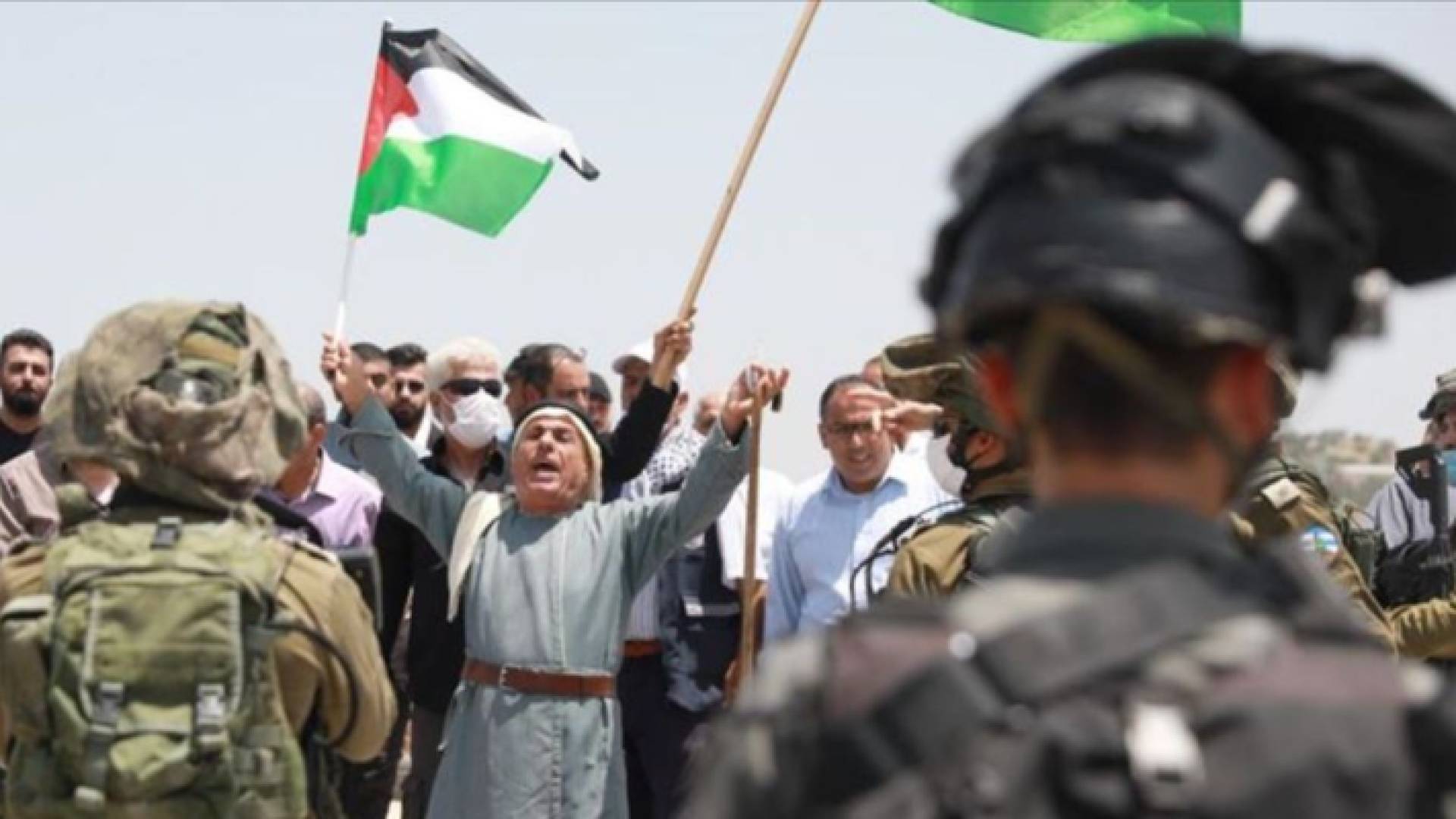 فلسطيني يحمل علم فلسطين أمام جيش الاحتلال