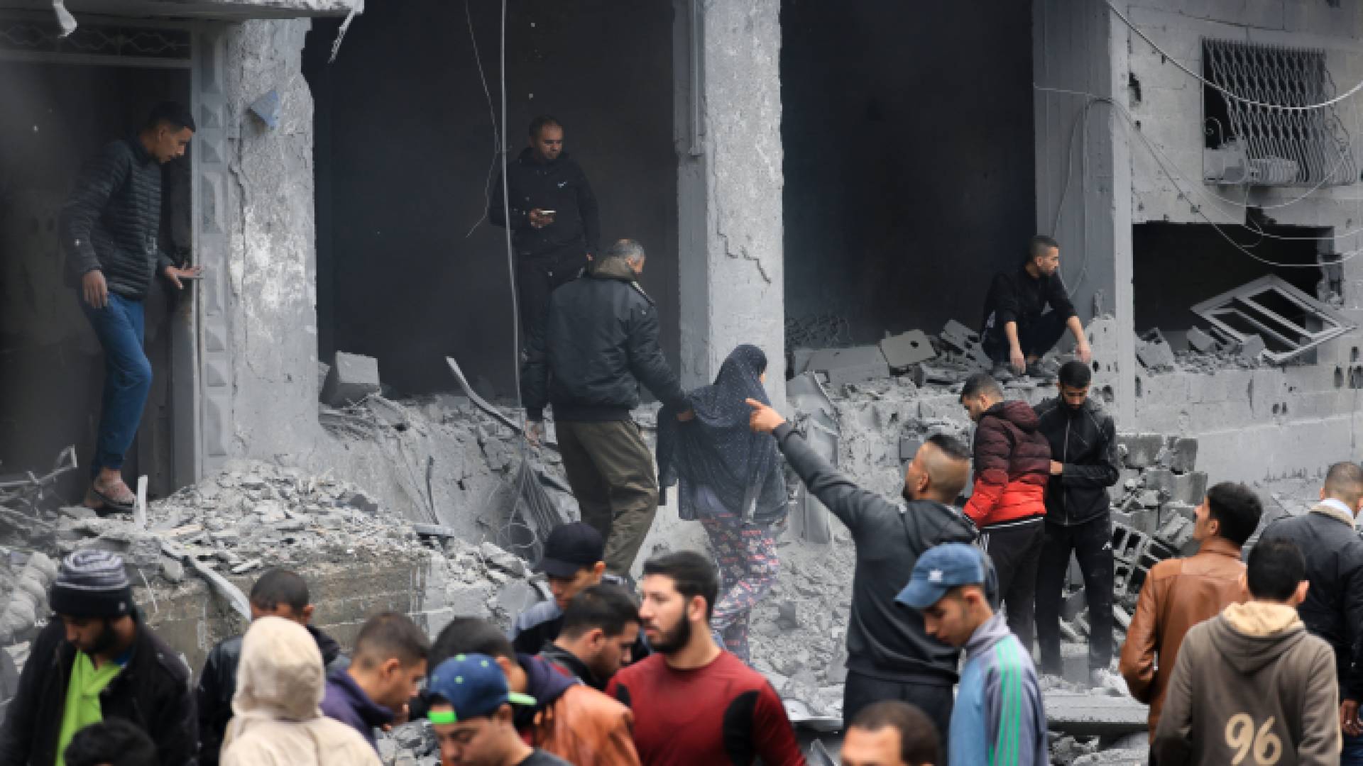 فلسطينيون بالقرب من أحد المنازل التي دمرت بقصف الاحتلال