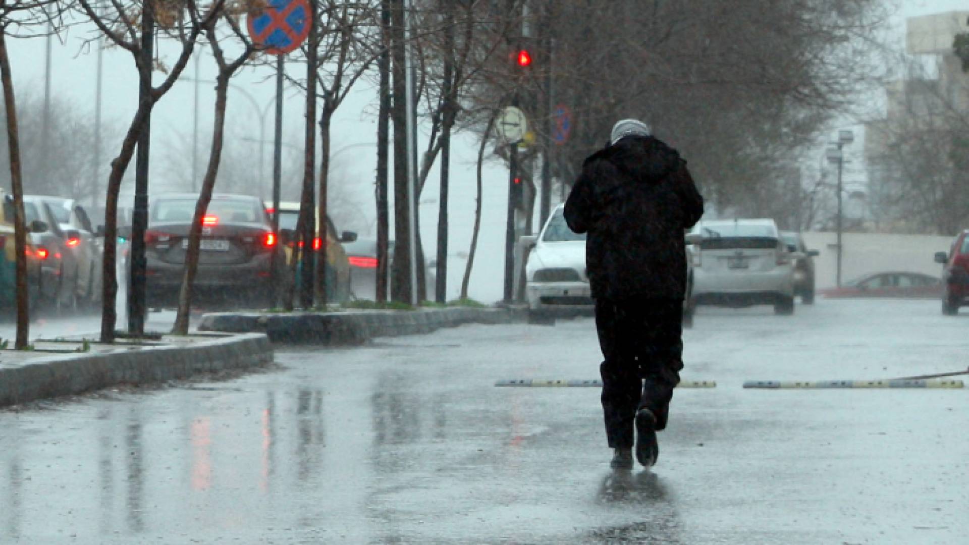 مواطن يسير في الشارع العام وسط الأجواء الباردة