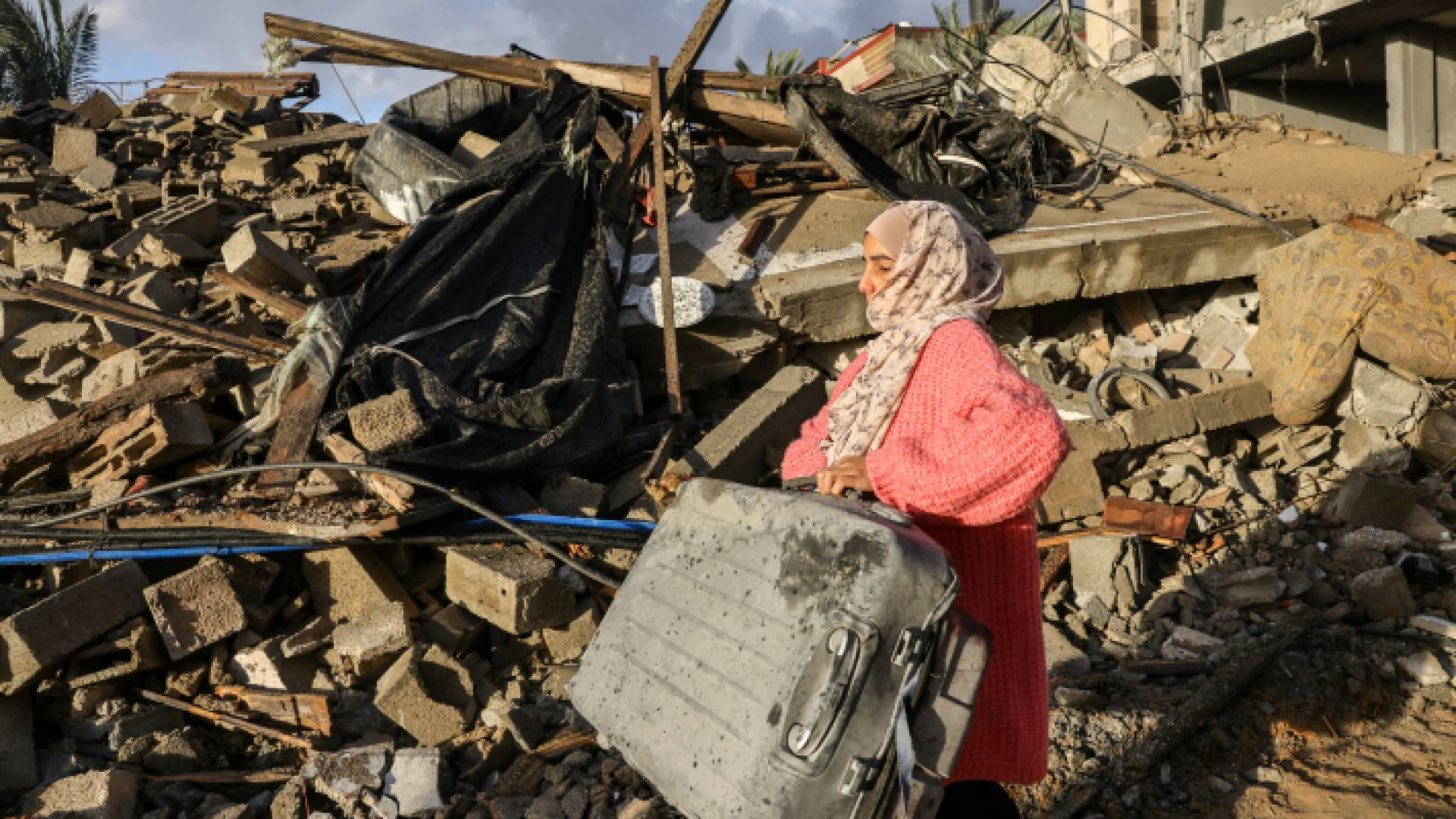فلسطينية تحمل حقيبة ملابس بعدما دمر الاحتلال منزلها في قطاع غزة