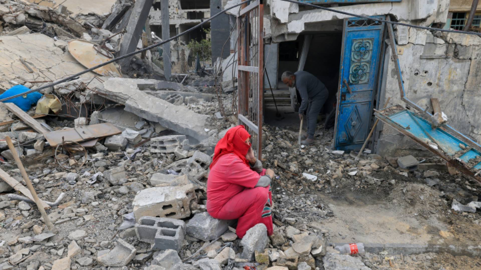 عائلة فلسطينية تجلس عند منزلها المدمر على يد جيش الاحتلال الإسرائيلي