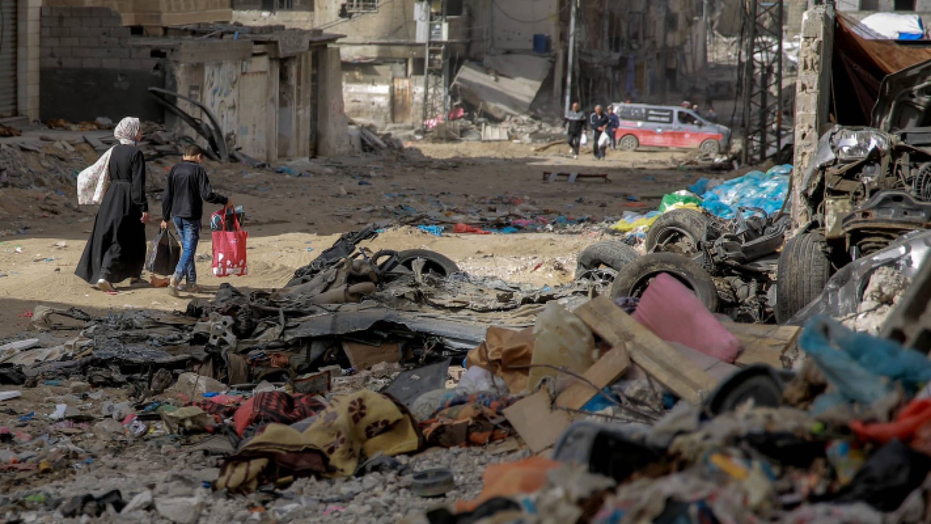 فلسطينيون يسيرون وسط أنقاض المباني المدمرة في مدينة غزة
