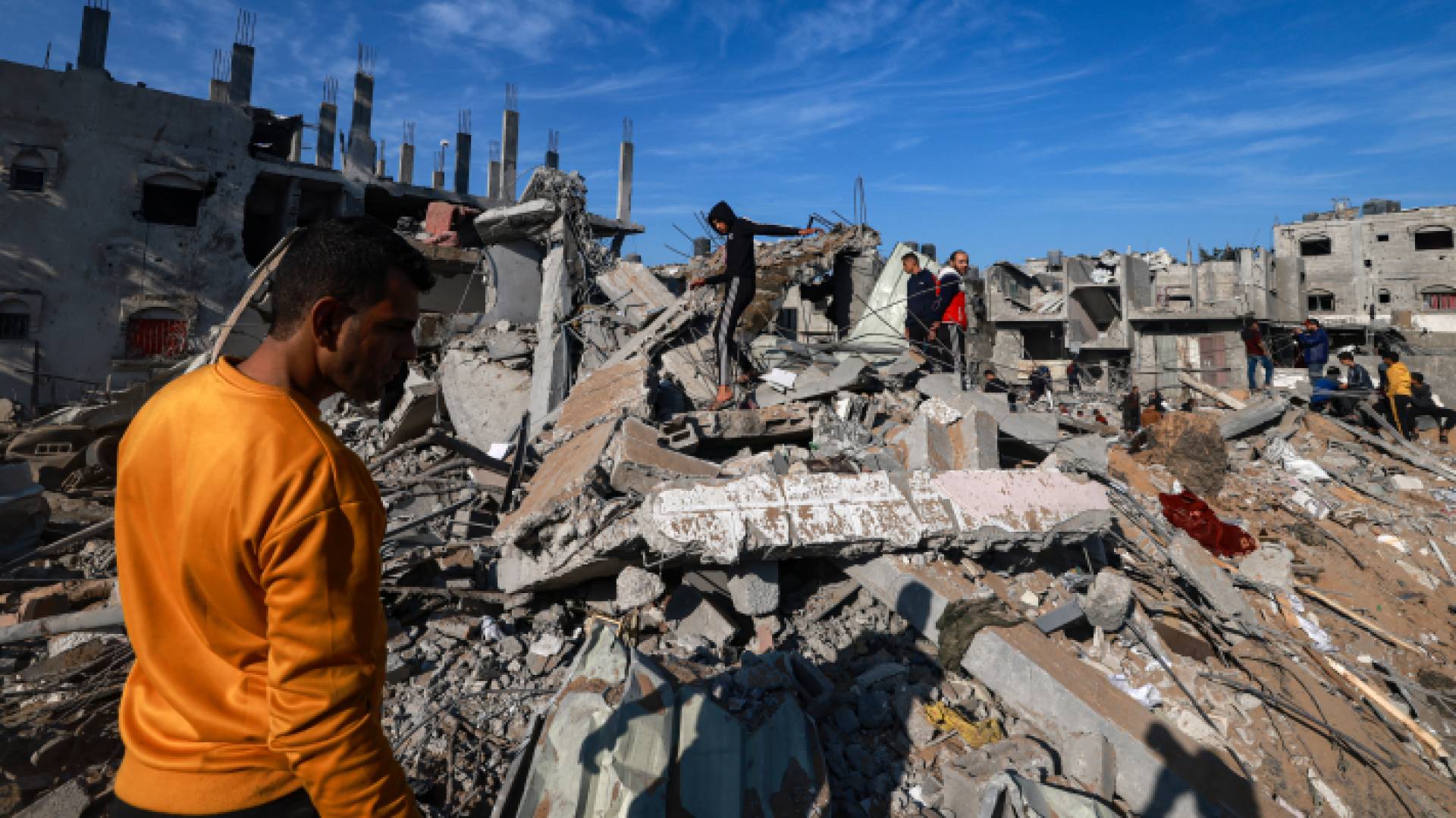 فلسطينيون يقفون عند ركام منزل دمره الاحتلال في قطاع غزة