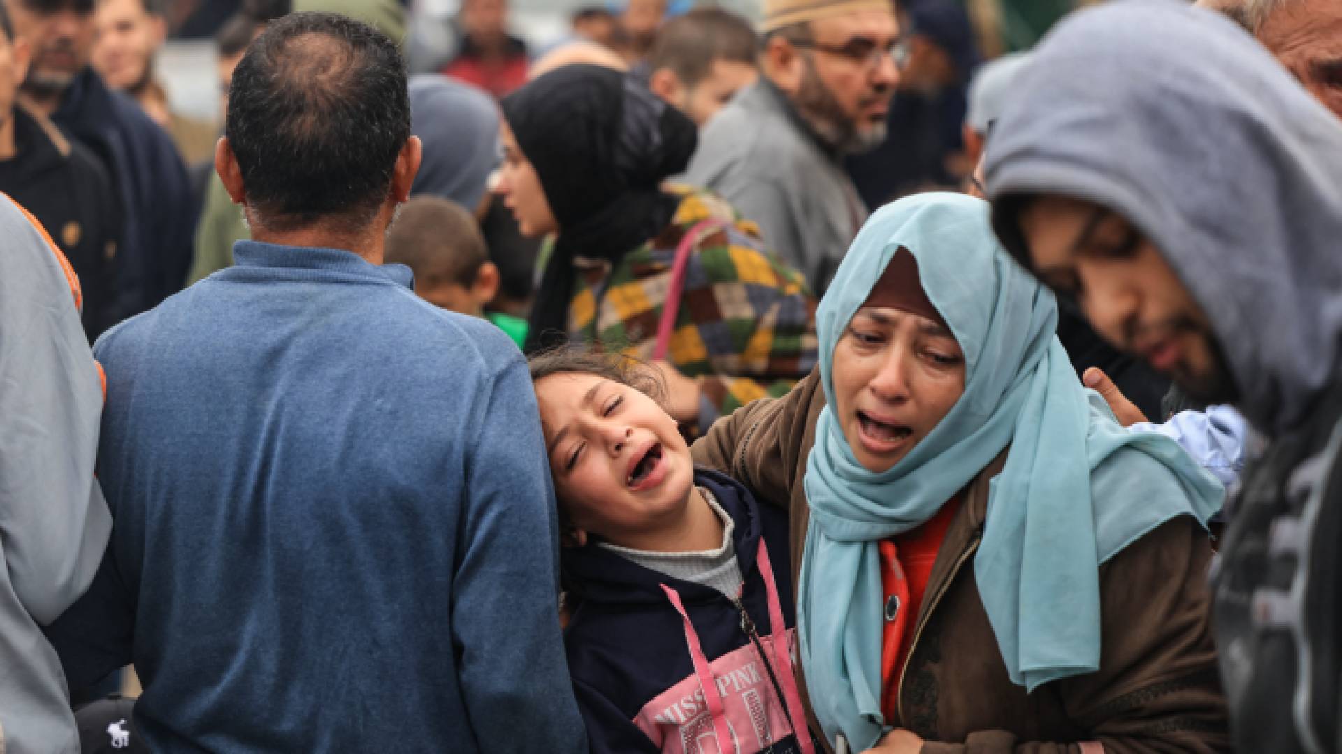 فلسطينية وطفلتها تبكيان بعد قصف الاحتلال منزلهما في قطاع غزة