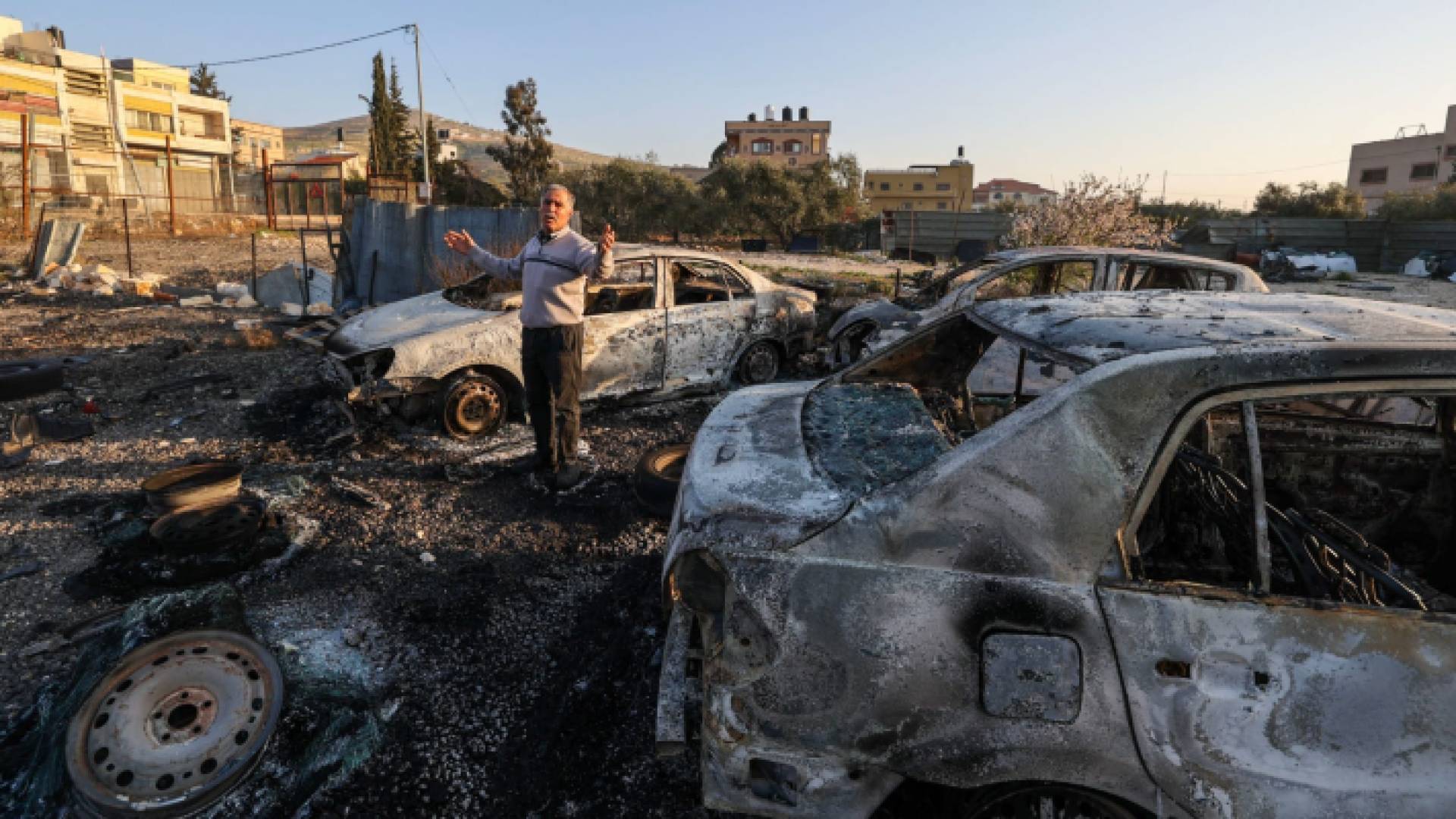 فلسطيني يقف عند مركبات حرقها مستوطنون في الضفة الغربية