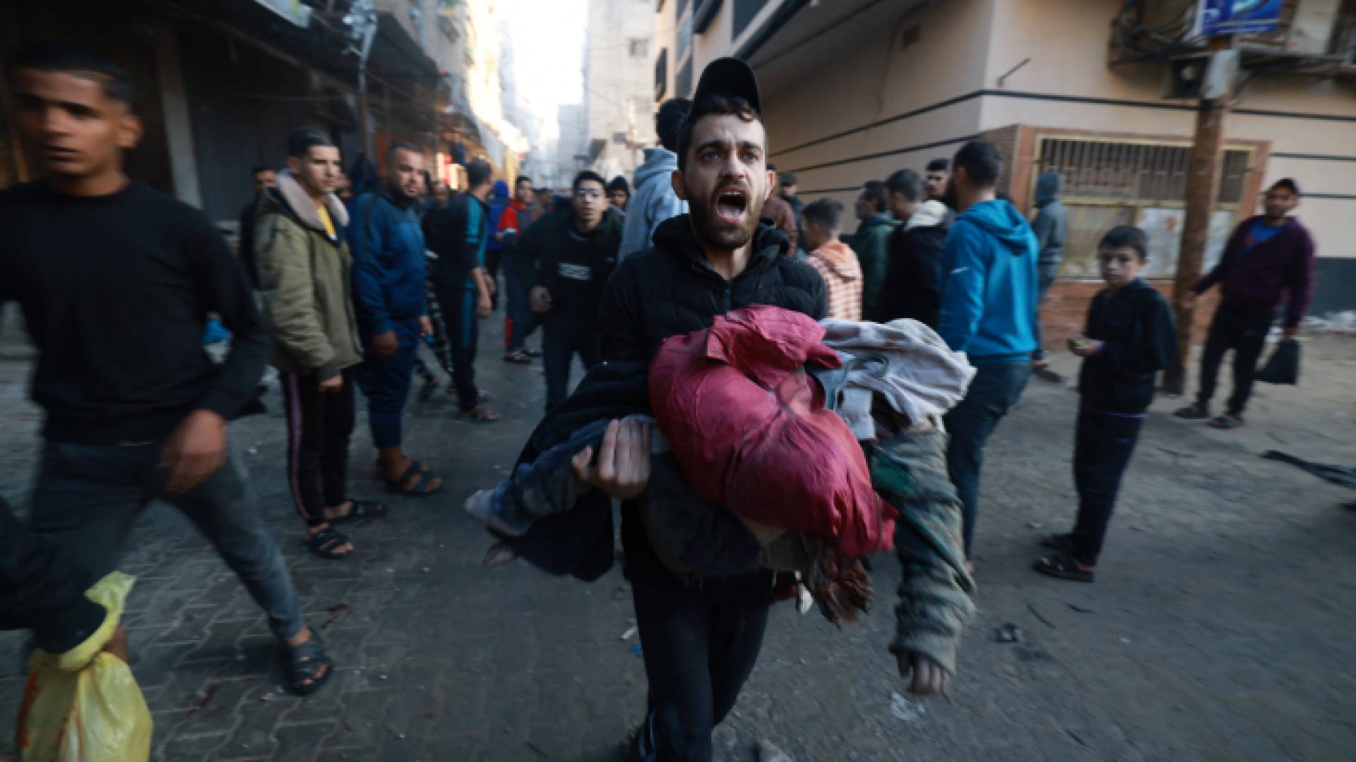 فلسطيني يحمل طفلته في قطتاع غزة بعد استهداف منزله