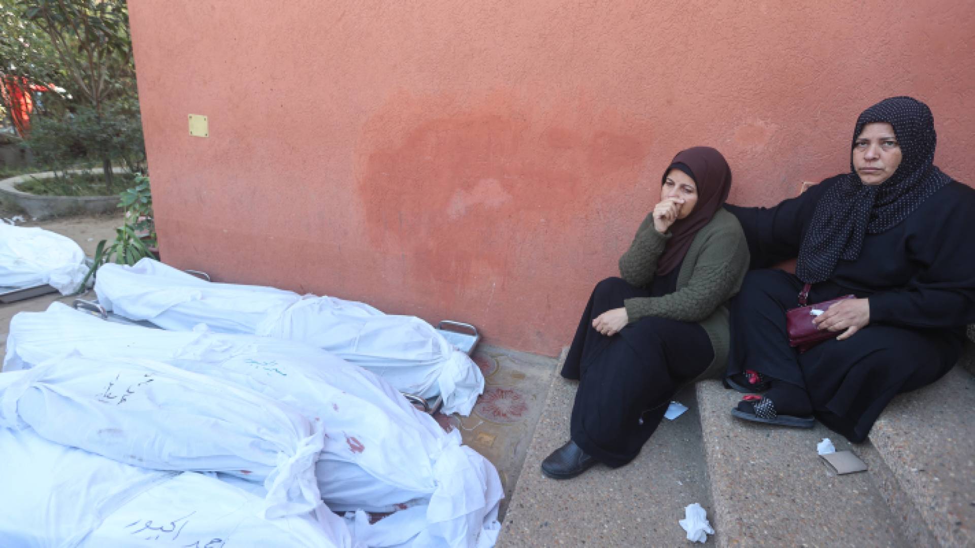 فلسطينيتان يجلسان قرب شهداء