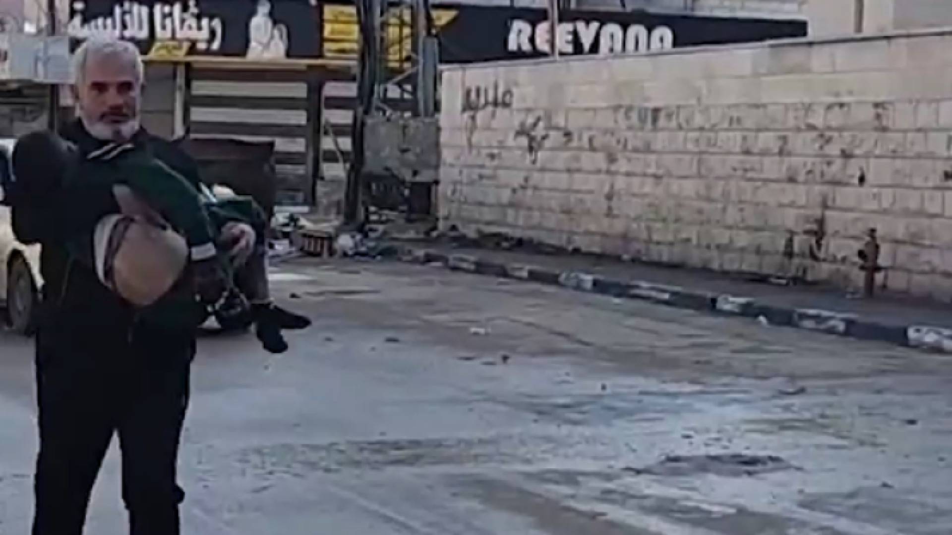 فلسطيني يحمل نجله بين يديه