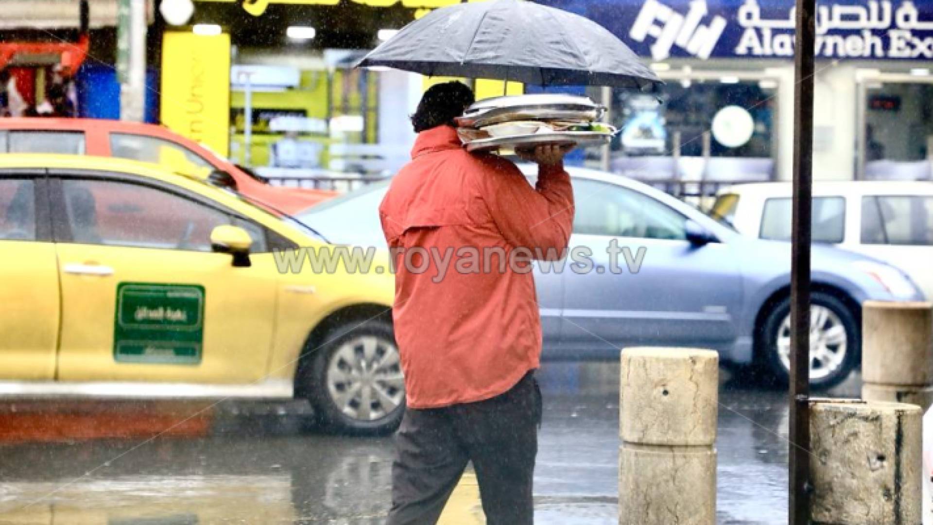 شخص يسير في أحد شوارع العاصمة اثناء هطول الأمطار