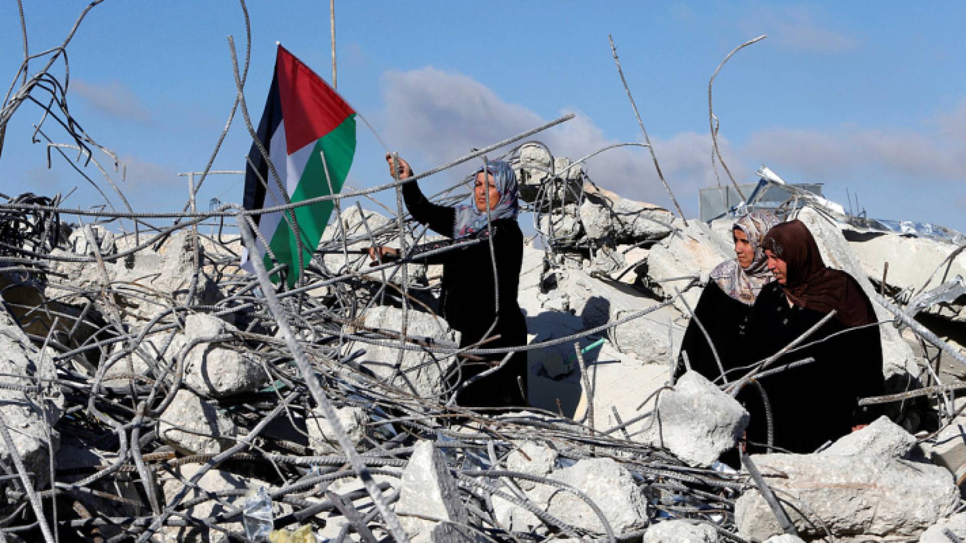 فلسطينية ترفع علم بلادها فوق ركام منزلها المدمر بقصف الاحتلال