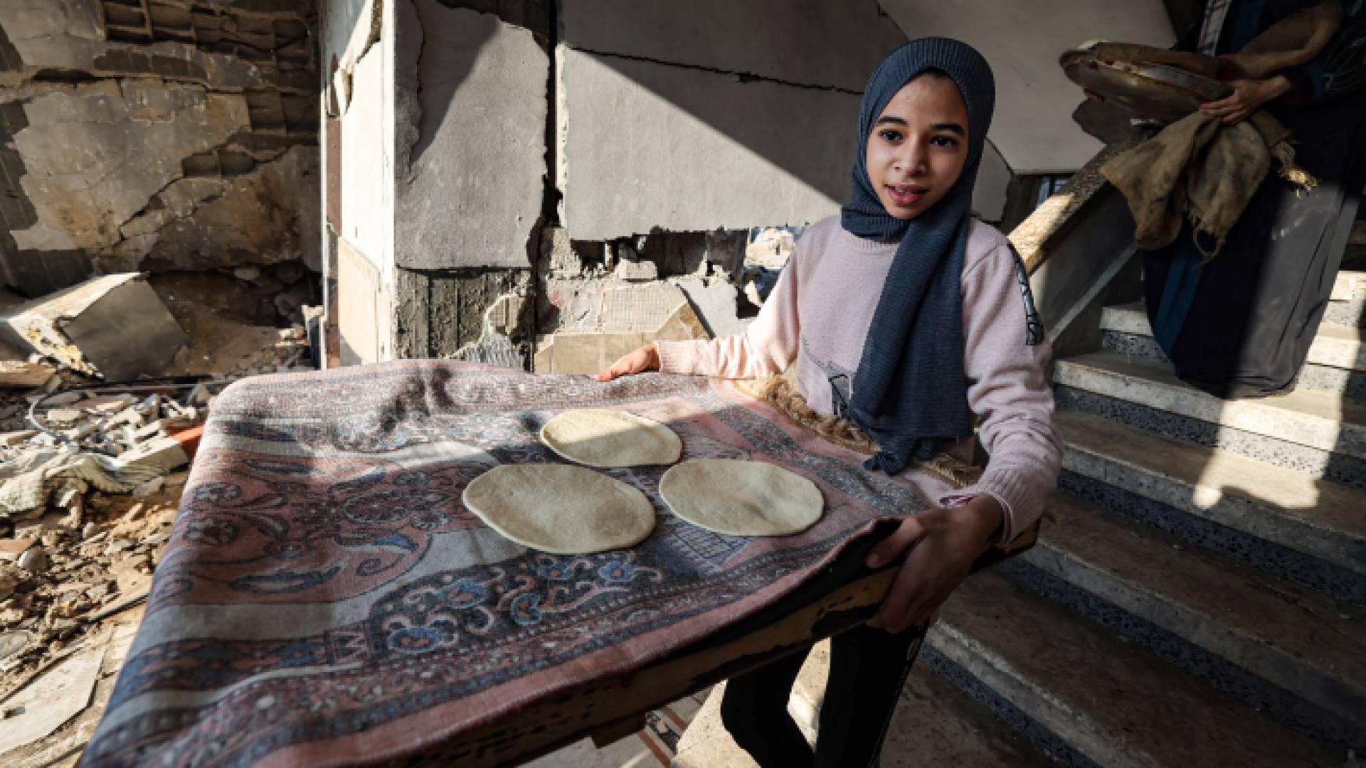 طفلة في غزة تحمل العجين لإعداد الخبز "أ ف ب"