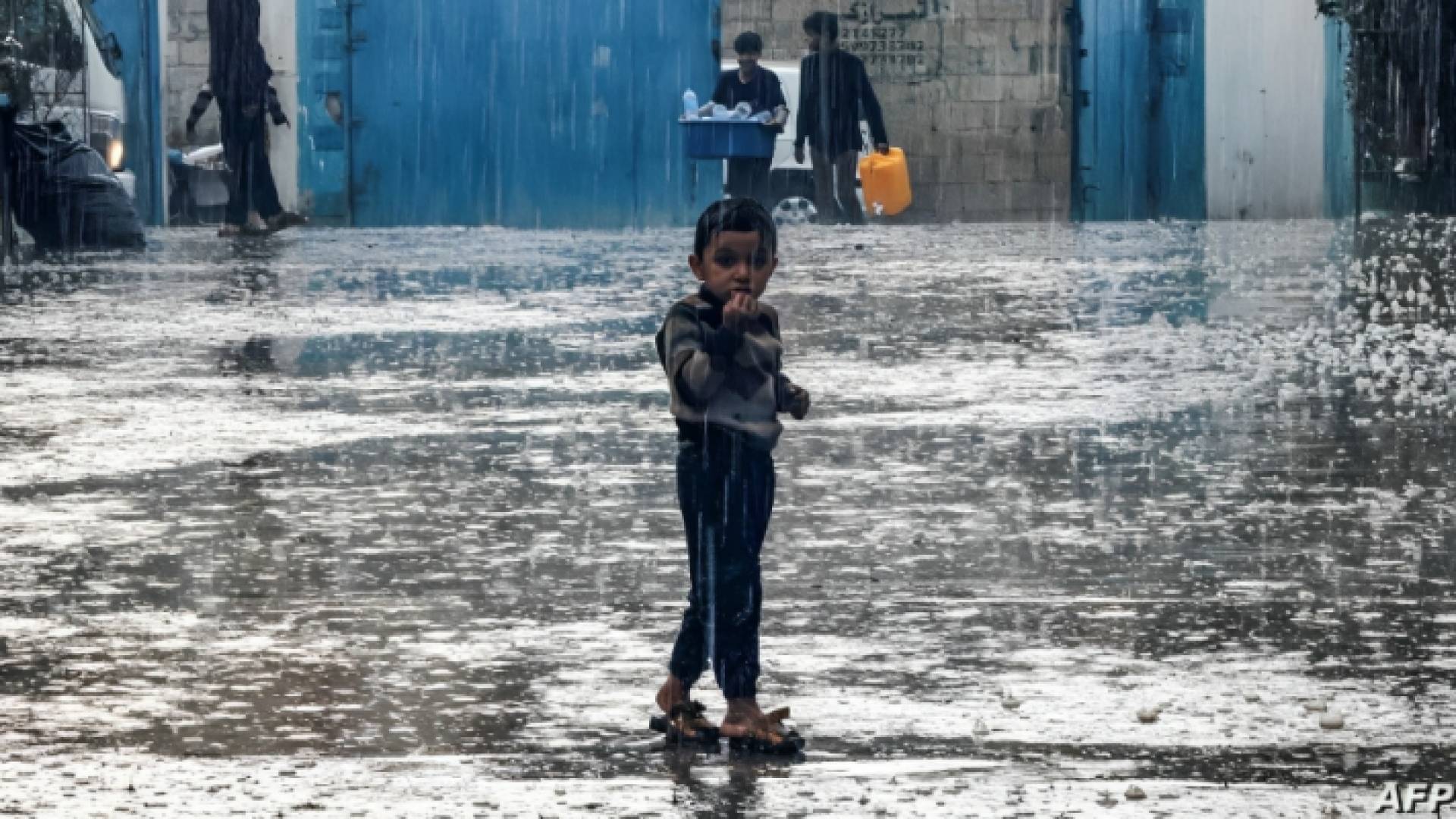 طفل يقف وسط هطول الأمطار الغزيرة في غزة
