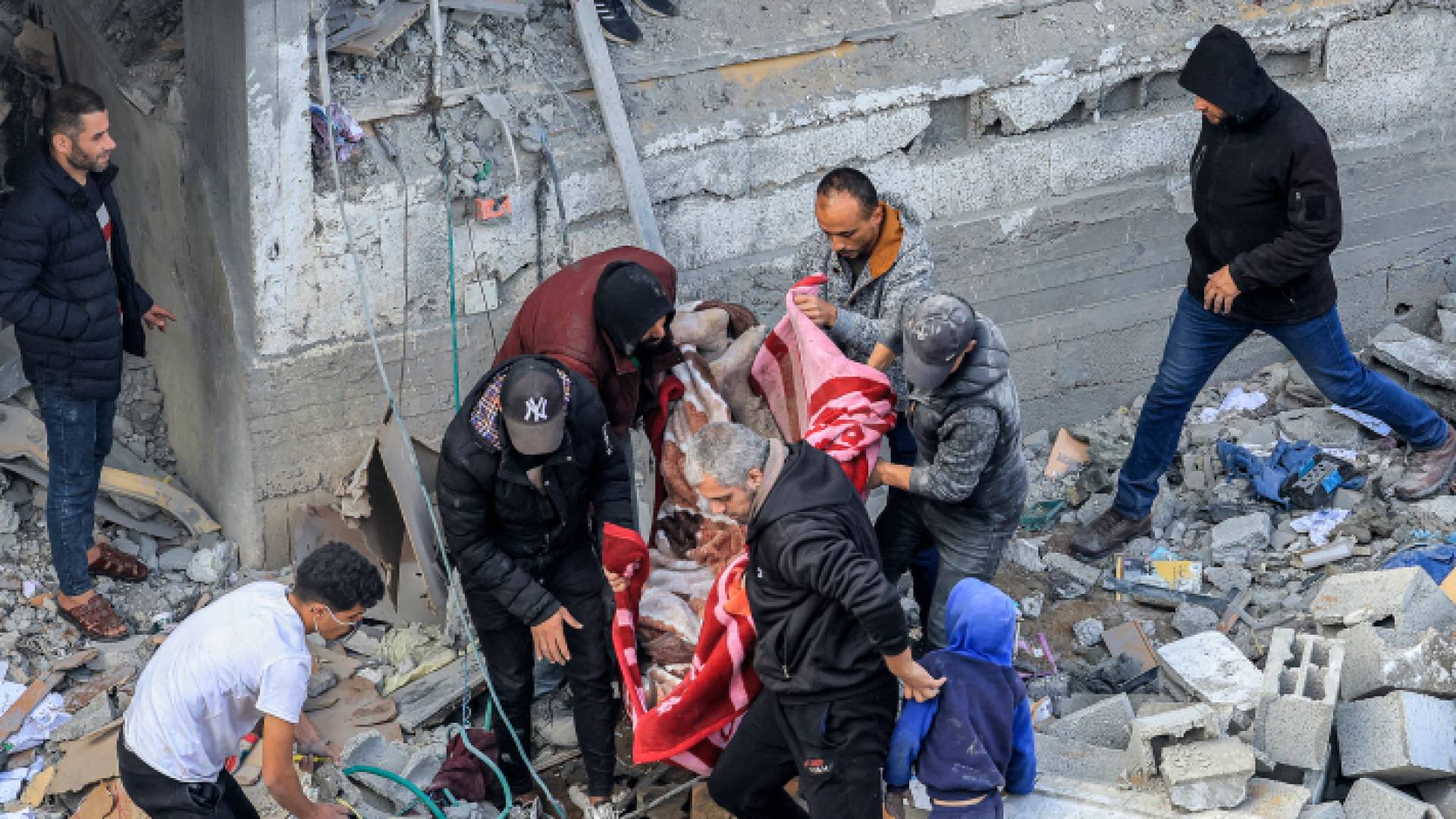 فلسطينيون ينتشلون شهداء في أعقاب غارة للاحتلال على مخيم المغازي - AFP