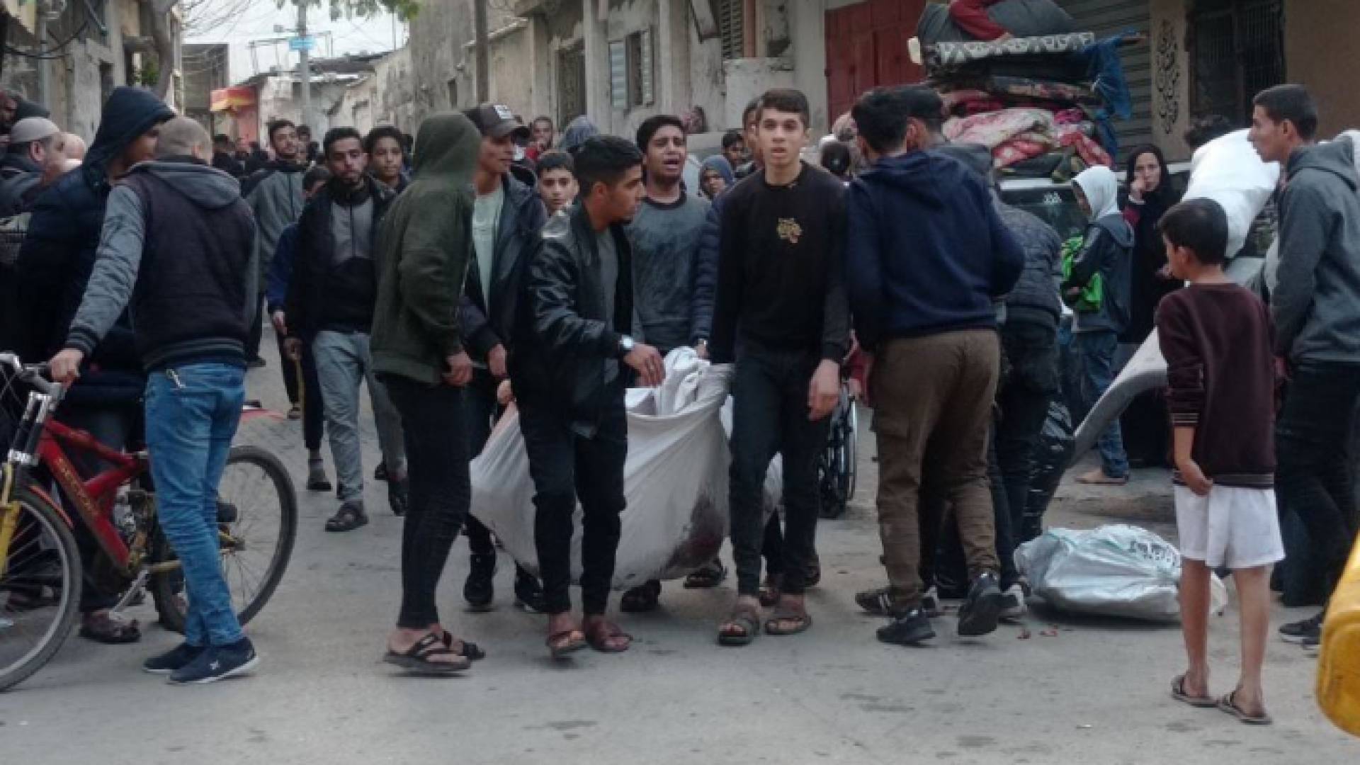 فلسطينيون يحملون شهيدا بعد استهداف مدرسة المغازي في قطاع غزة
